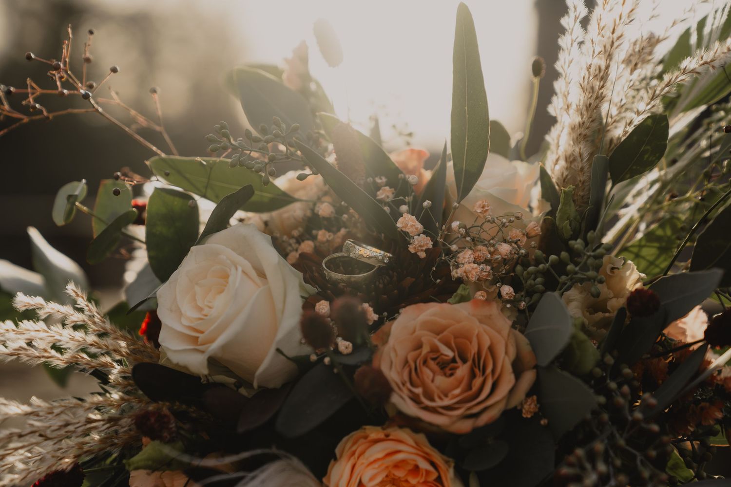 Close-up of romantic peach and white wedding floral arrangements with greenery.
