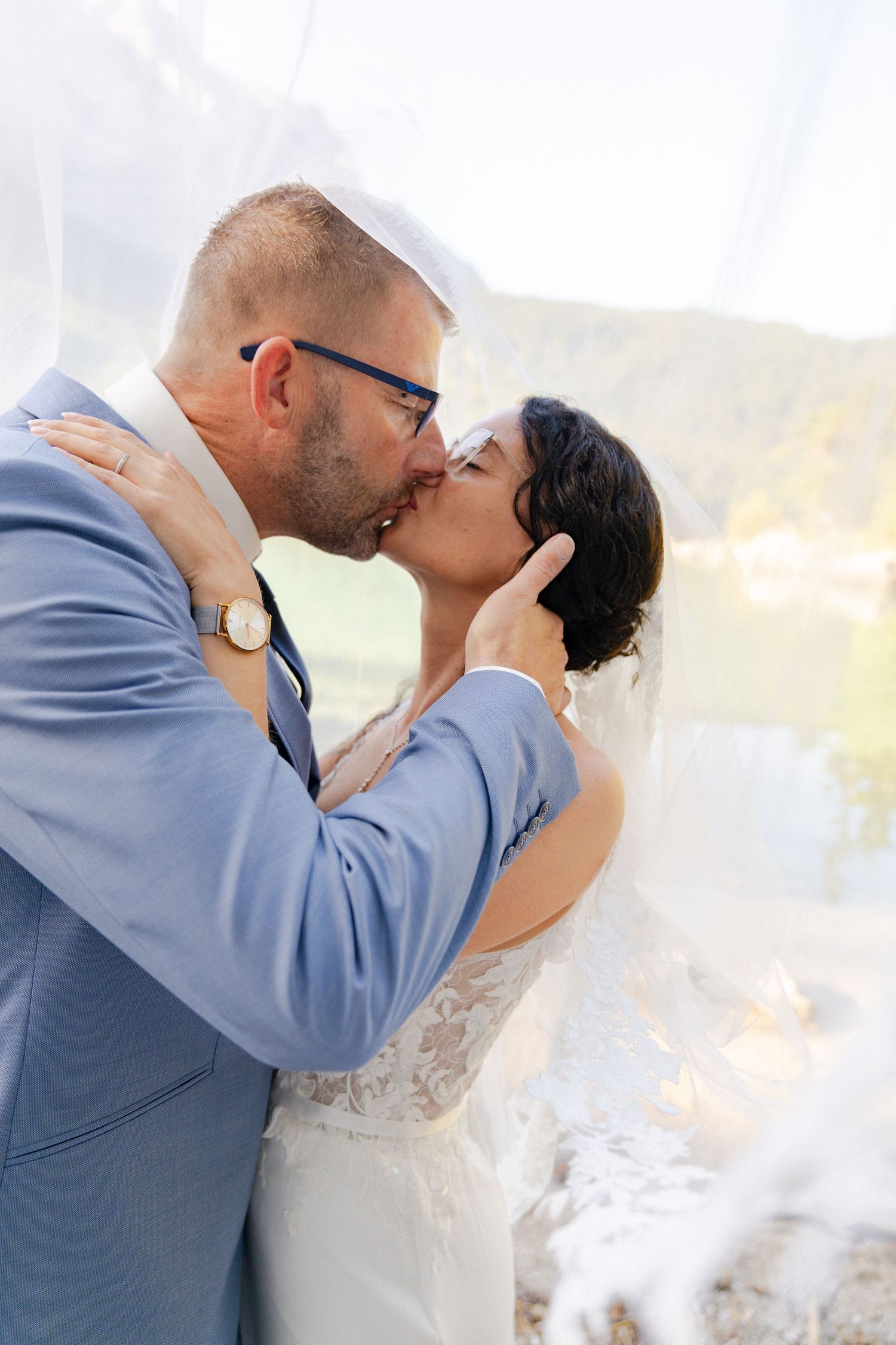 A couple shares romantic kisses in a series of wedding photos wearing blue and white attire against a soft background.