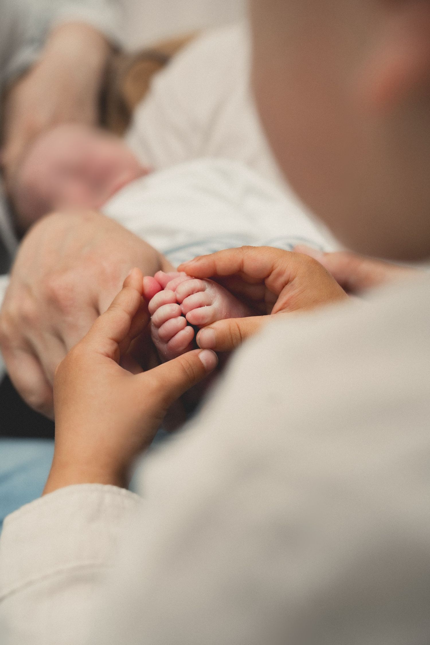 Close-up of adult hands gently holding a newborn baby's tiny feet, symbolizing love and new parenthood.