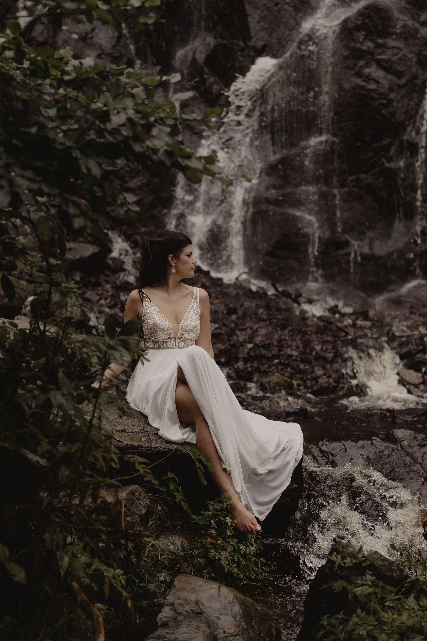 Ethereal bridal portraits in a flowing white dress near a misty forest waterfall.