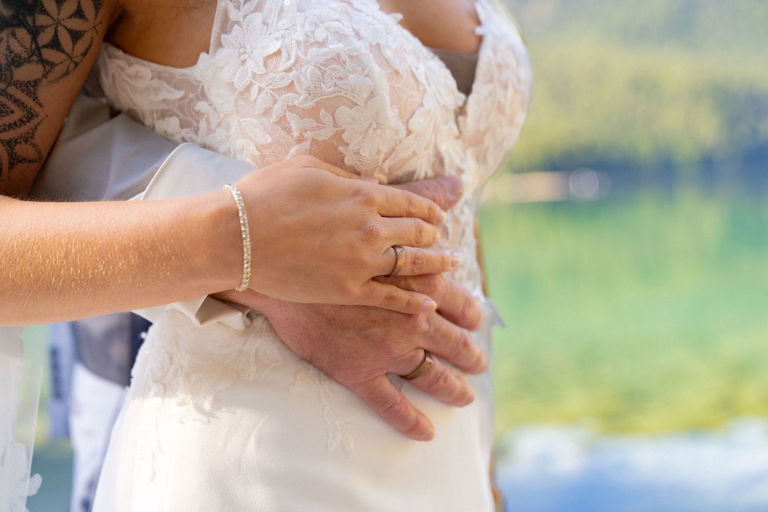 Close-up details of a couple's tender embrace during their lakeside wedding ceremony.