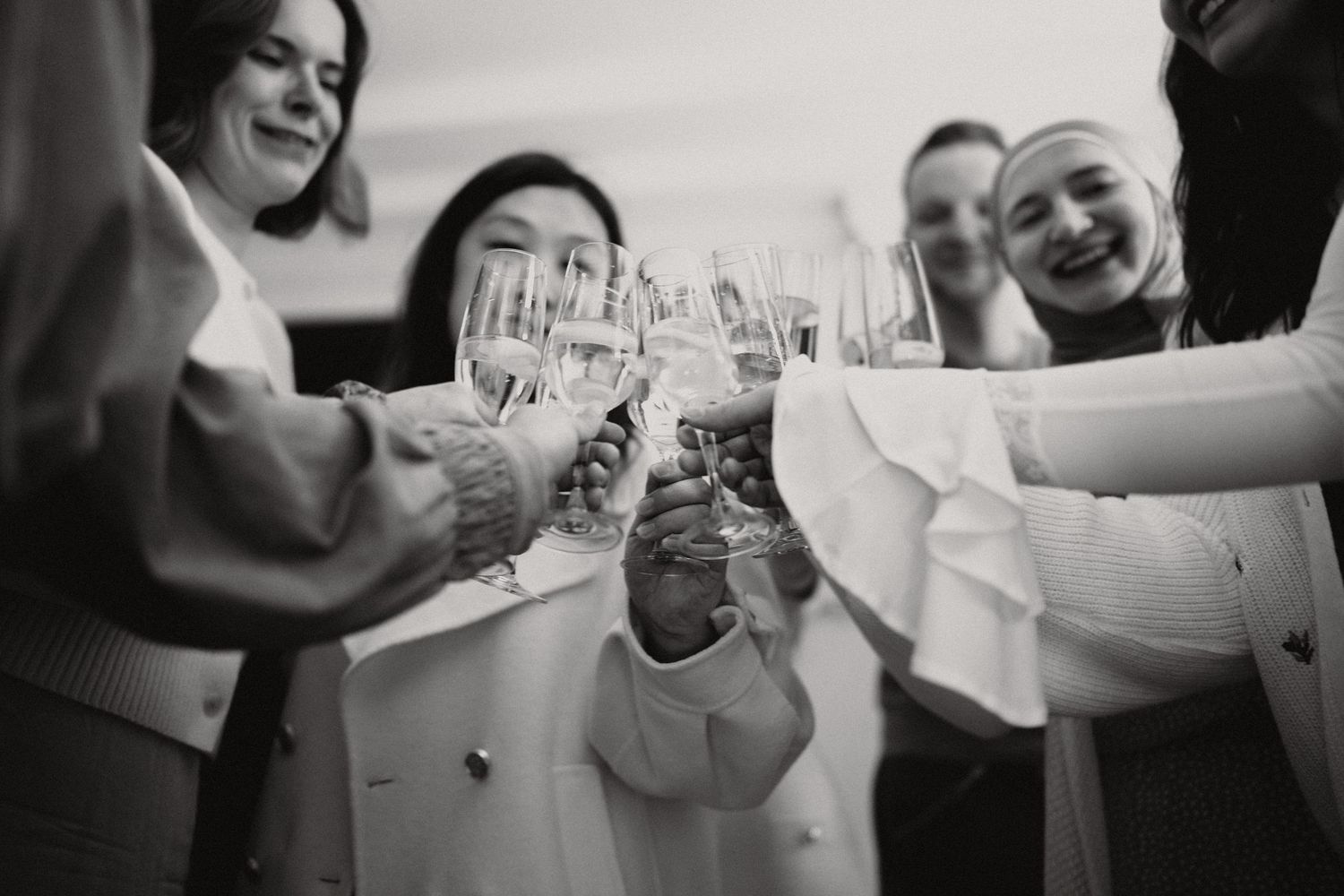 Black and white photo of women joyfully toasting with champagne glasses at a celebration.