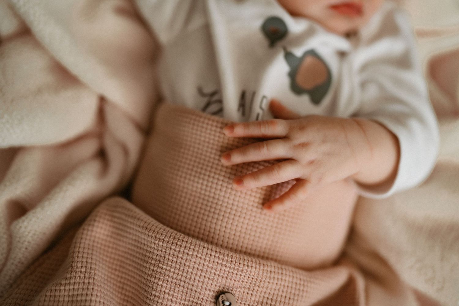 Close-up view of hands resting on textured beige fabric in natural light.