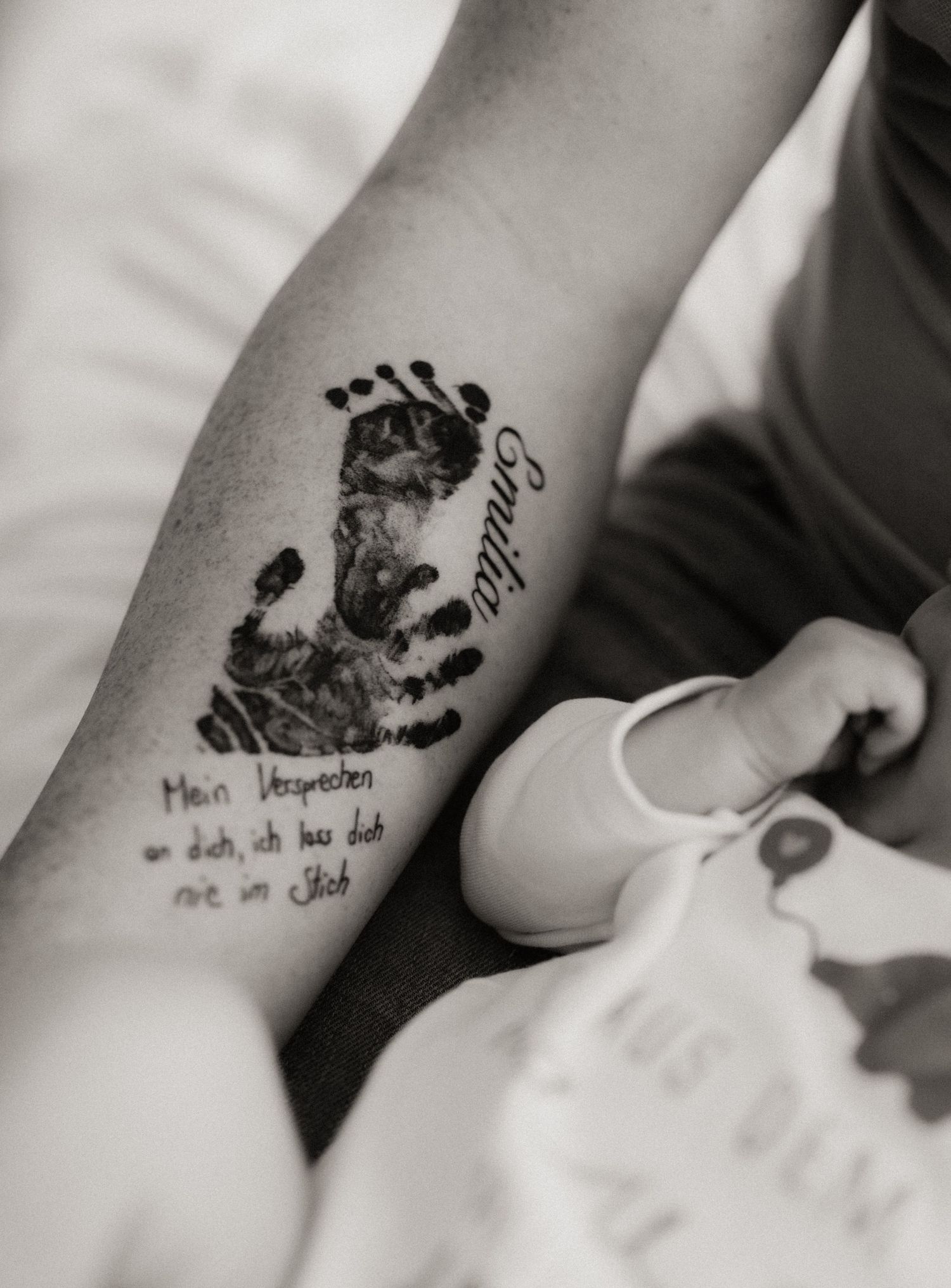 A series of black baby handprint and footprint ink impressions arranged in a row on white paper.