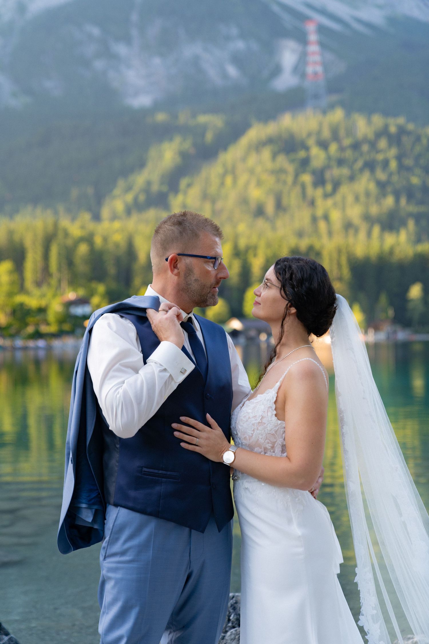A romantic wedding photo sequence showing a couple embracing by a scenic mountain lake with evergreen forests in the background.