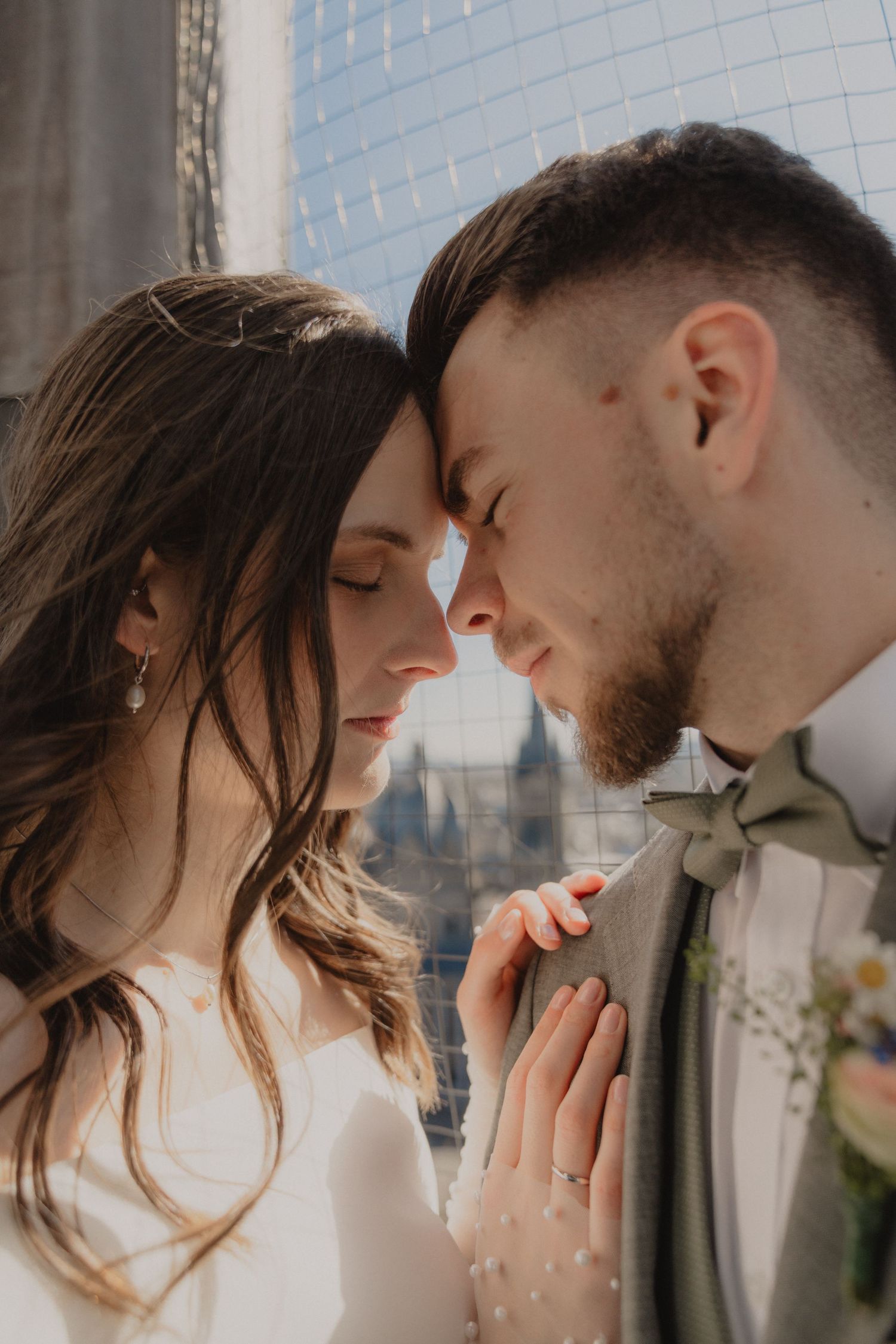 Intimate romantic moment captured against city window backdrop.