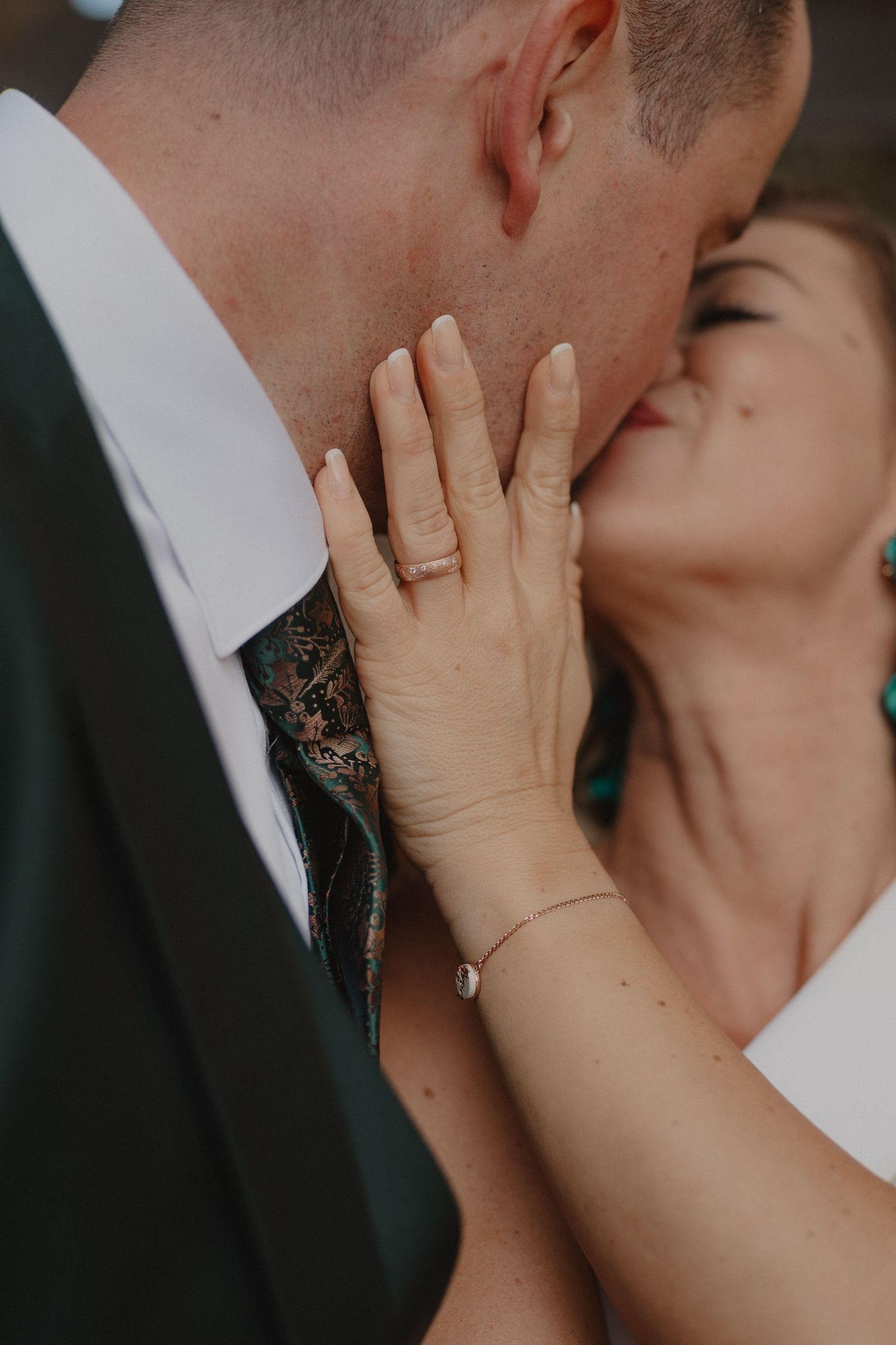 Close-up intimate moment between newlyweds with focus on hands and formal attire.