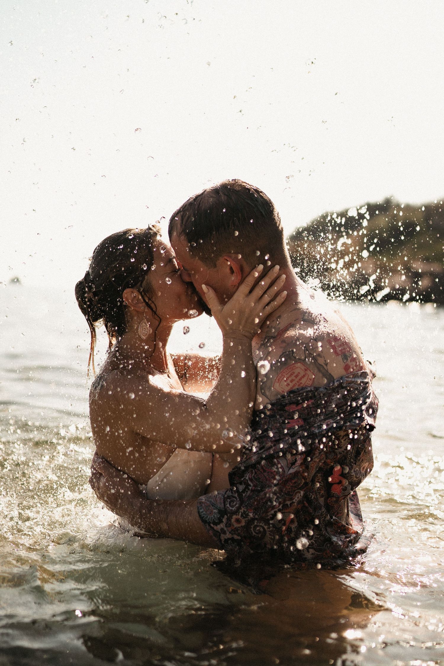 A romantic moment captured in the ocean with water droplets sparkling in the sunlight.