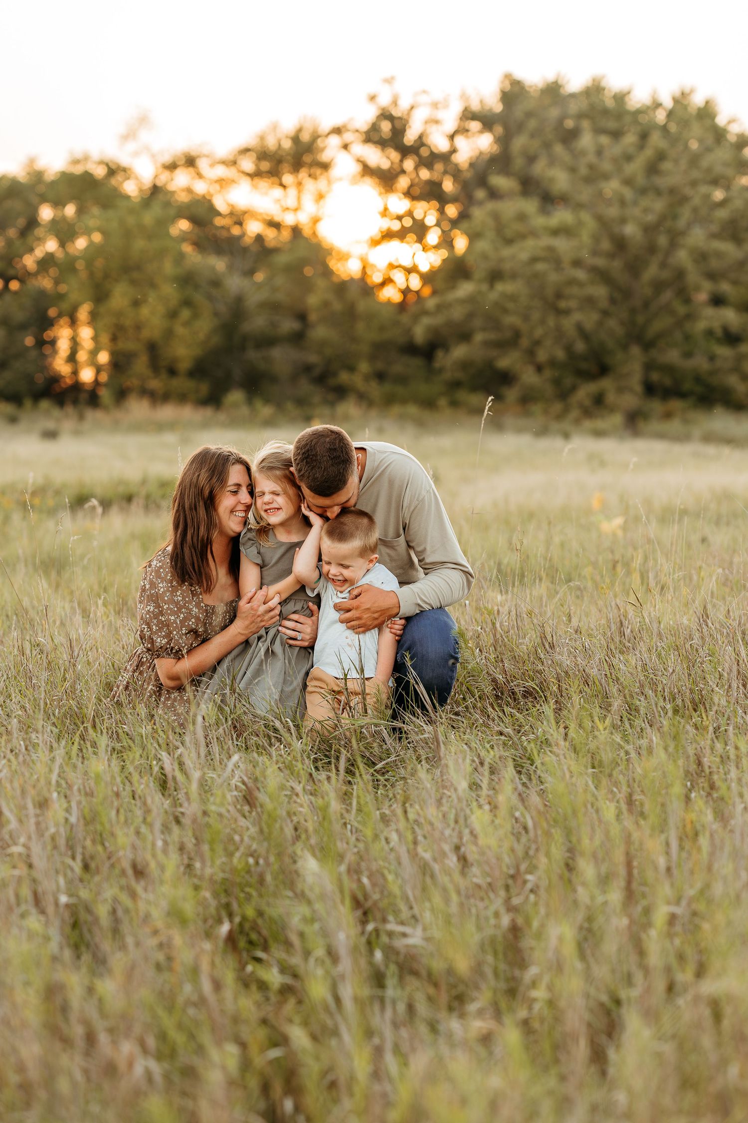 A family laughing together in a grassy field during sunset in lake country WI