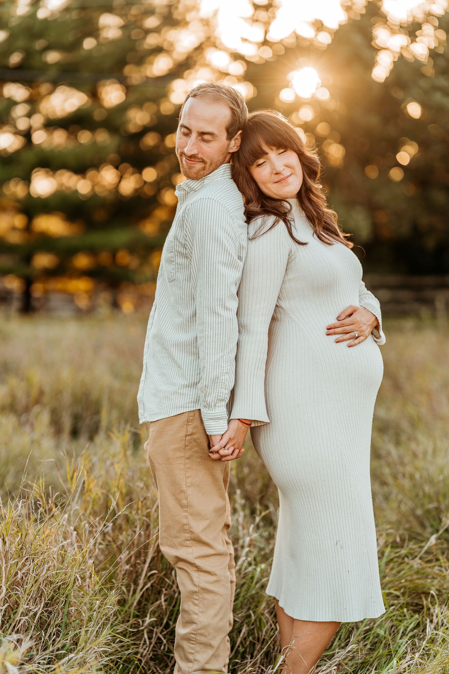 Family maternity photoshoot in a golden field at sunset wearing white and beige outfits.
