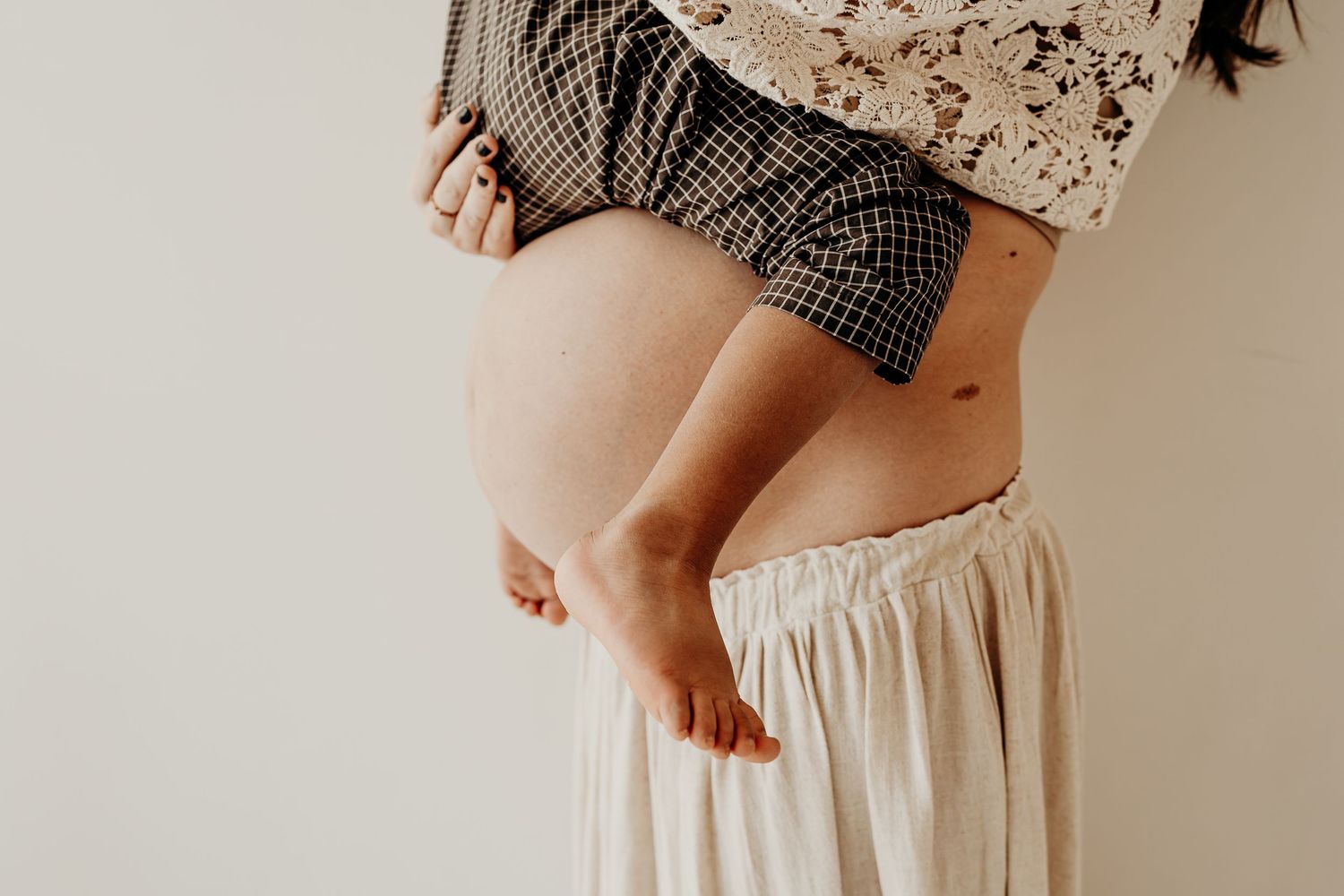Maternity photographer in East Troy, Wisconsin, capturing a soft, side profile of a mom holding her baby bump. with a child sitting on her