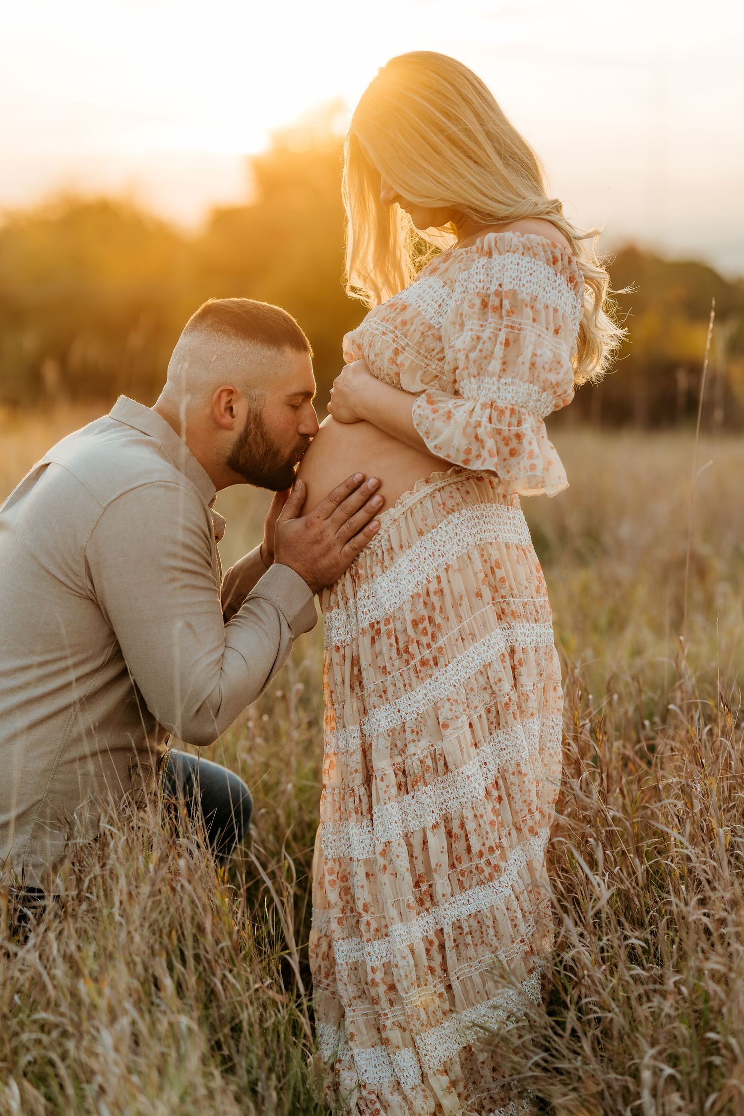 A couple shares an intimate moment in a golden sunlit field during a maternity photo session at sunset in the Wisconsin Lake Country