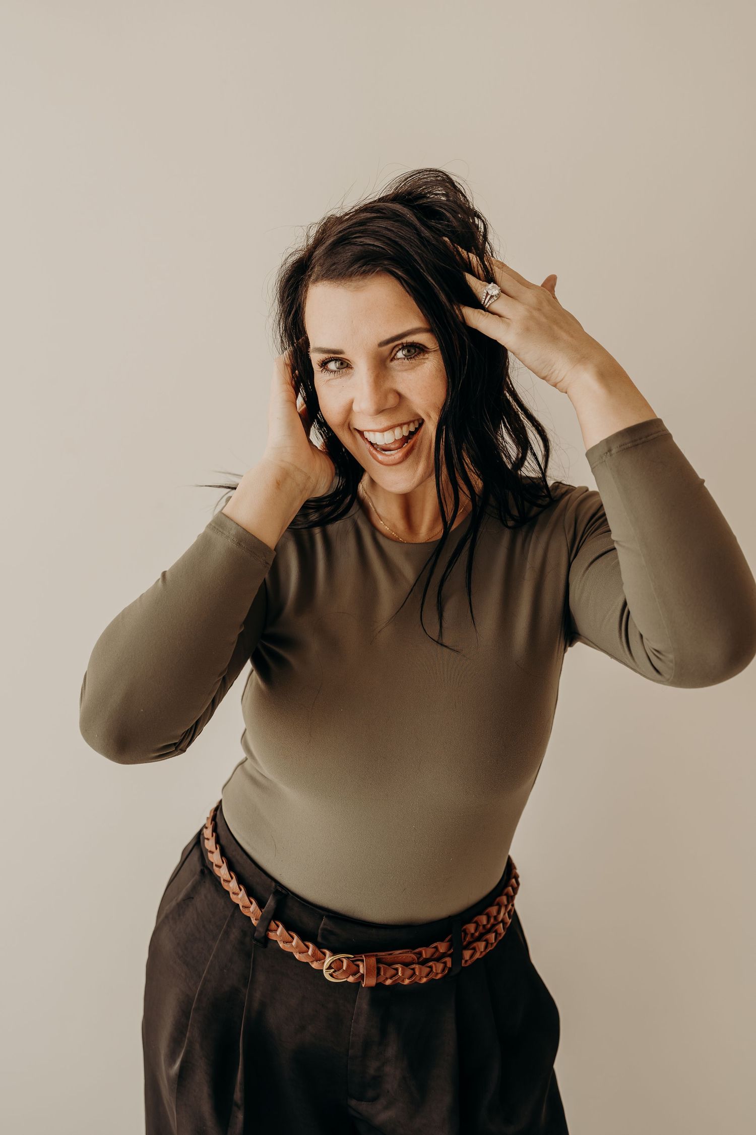 Hair and makeup artist portrait with playful pose in natural light studio
