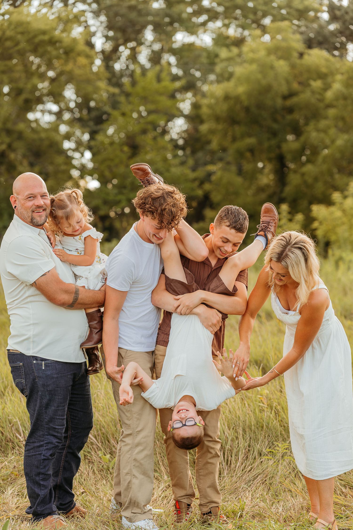 A family plays and laughs together in a grassy field session captured by Blankslate Photography, a wisconsin family photographer