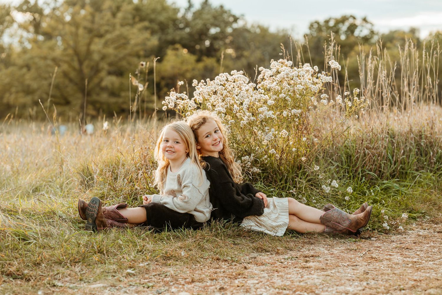 Two girls lying in a golden field of tall grass at sunset during an outdoor photo session in Delafield WI