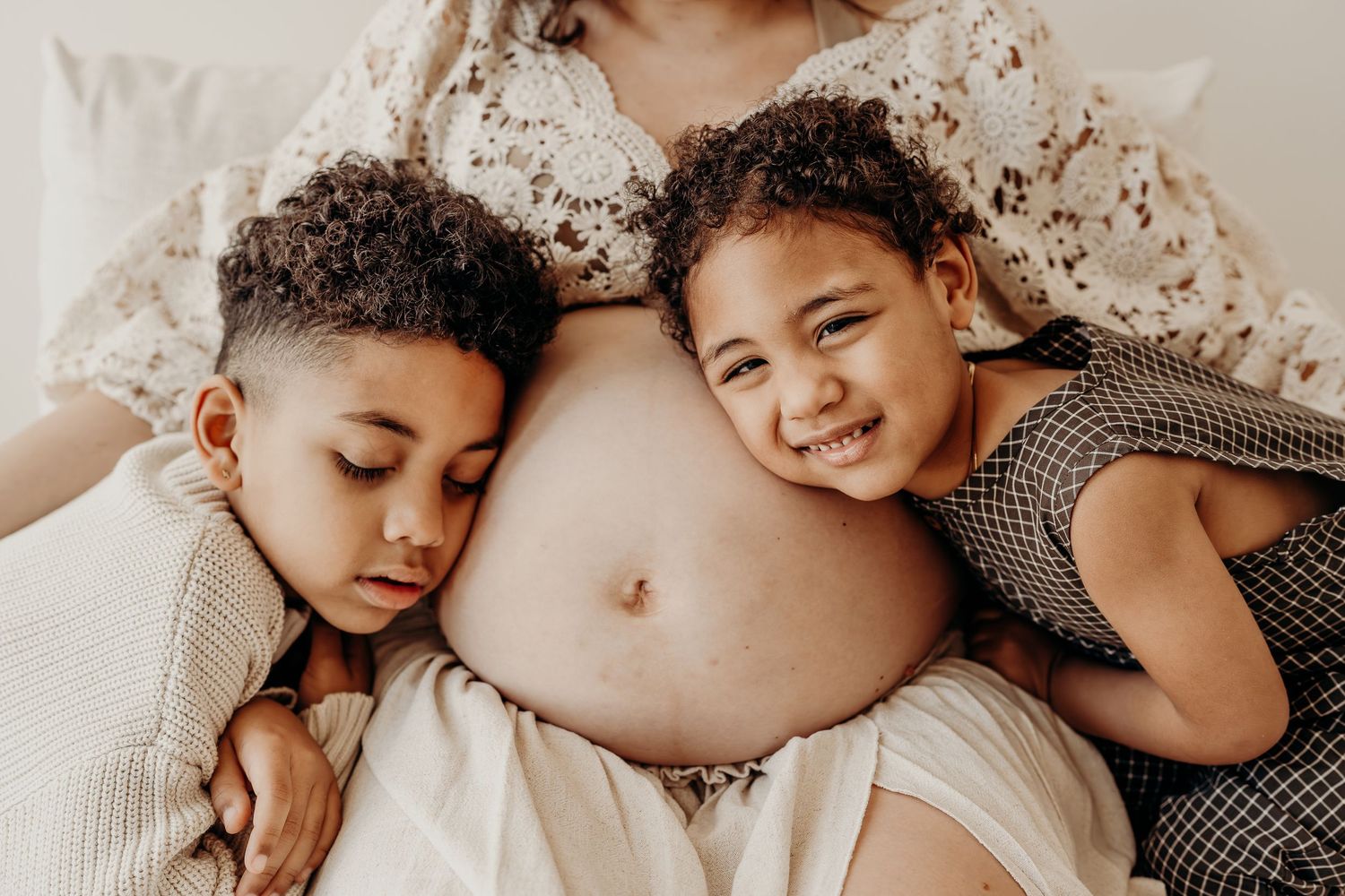 Maternity photographer in East Troy, Wisconsin photographing parents and their little one snuggled together on the studio bed.