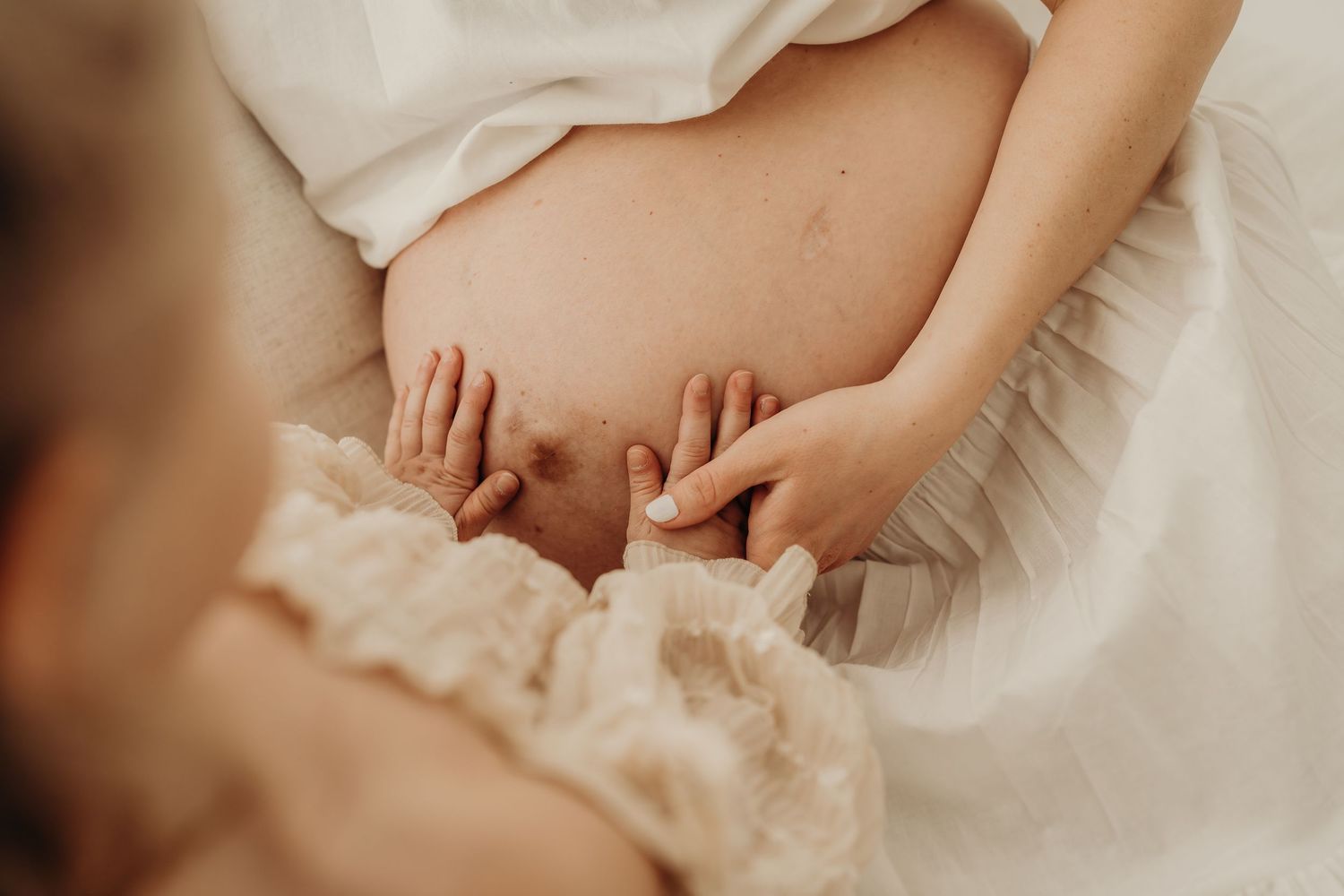 a child touching her mom's pregnant belly