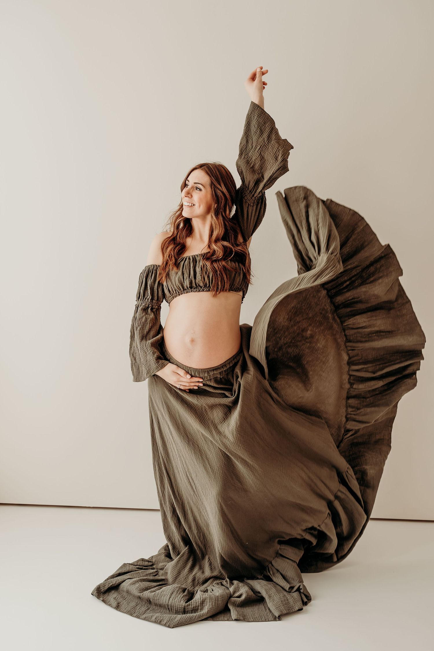 Artistic maternity photo series showing flowing olive dress movement against white backdrop in five sequential poses.
