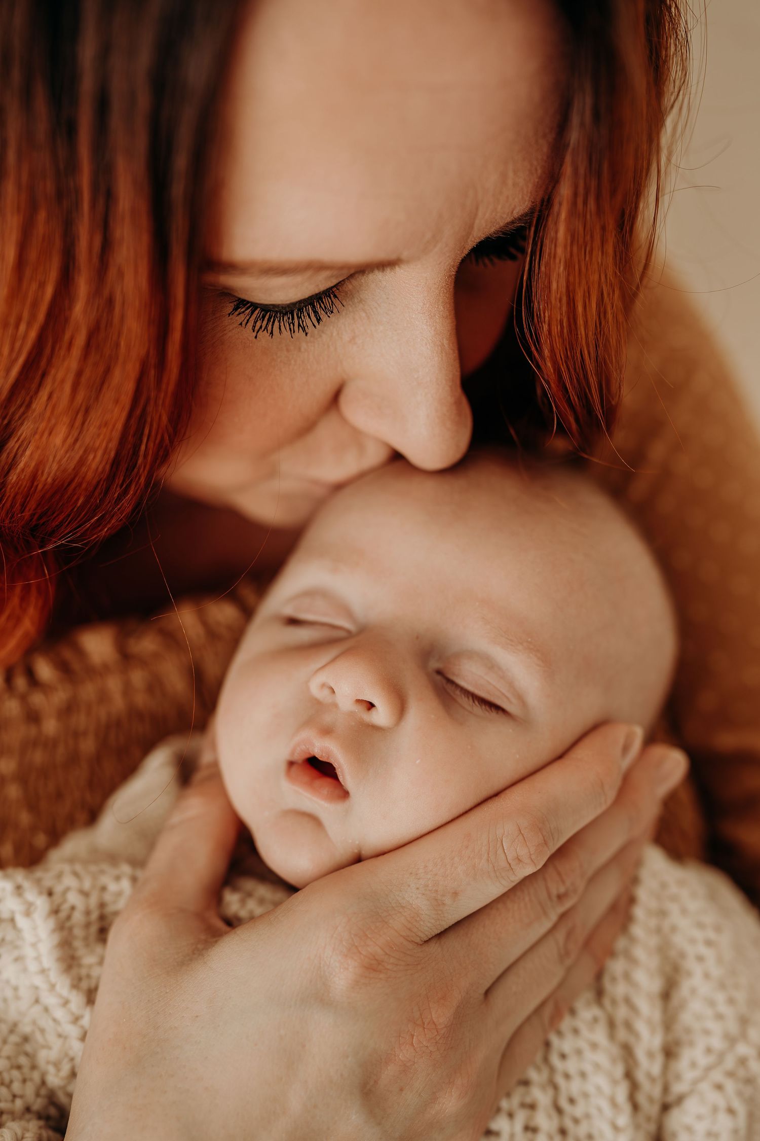 Close-up artistic portrait showing gentle touch and intimacy in warm tones during the studio newborn session.