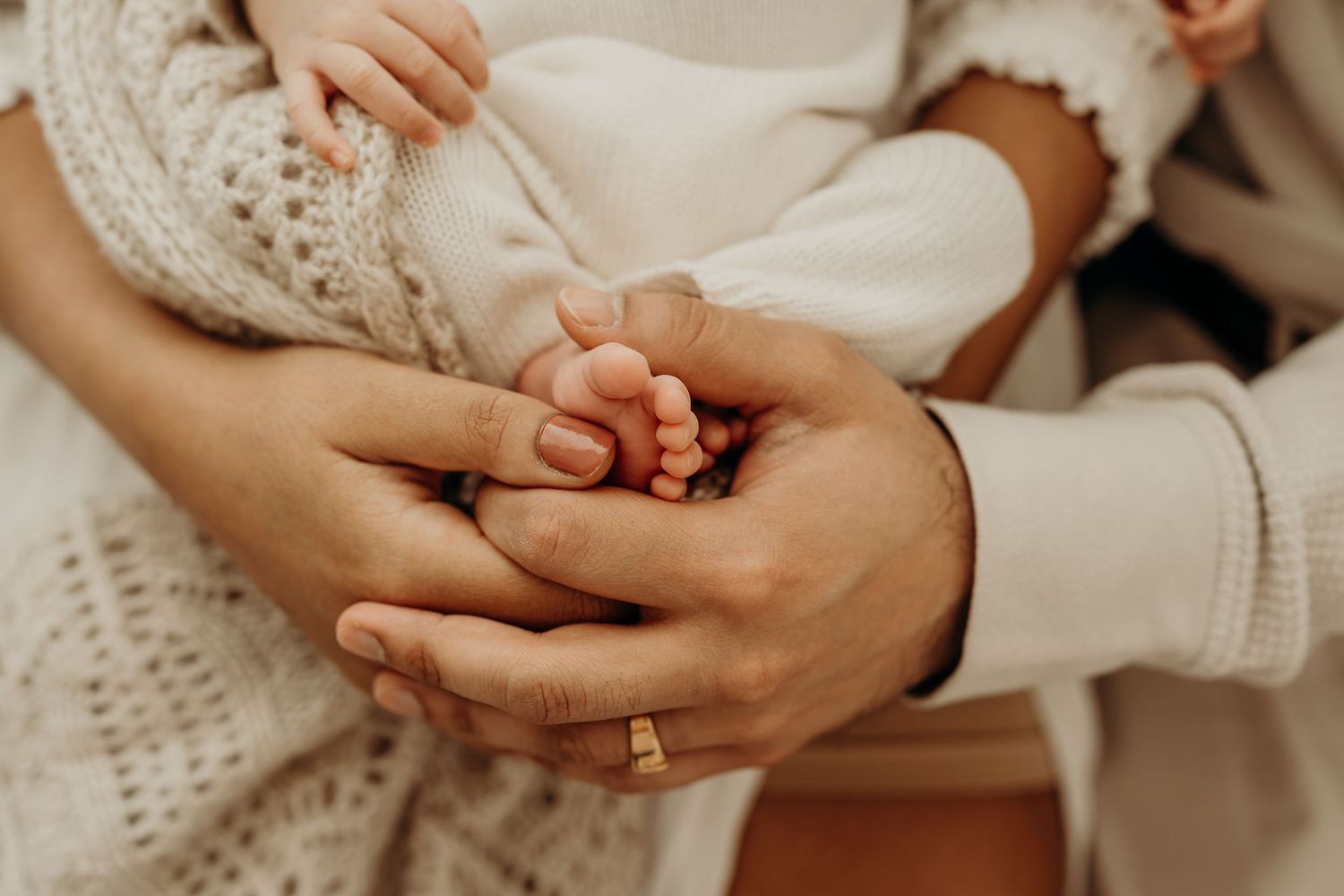 Parents tenderly hold their newborn baby's tiny feet in their hands, symbolizing new life and family love.