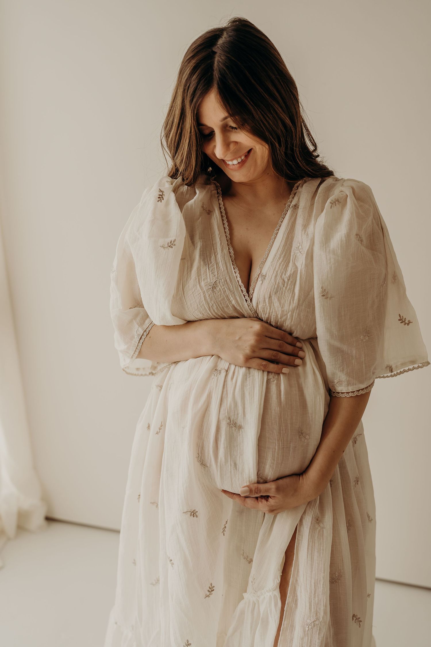 Dreamy maternity session featuring flowing white dress with delicate embroidery details.