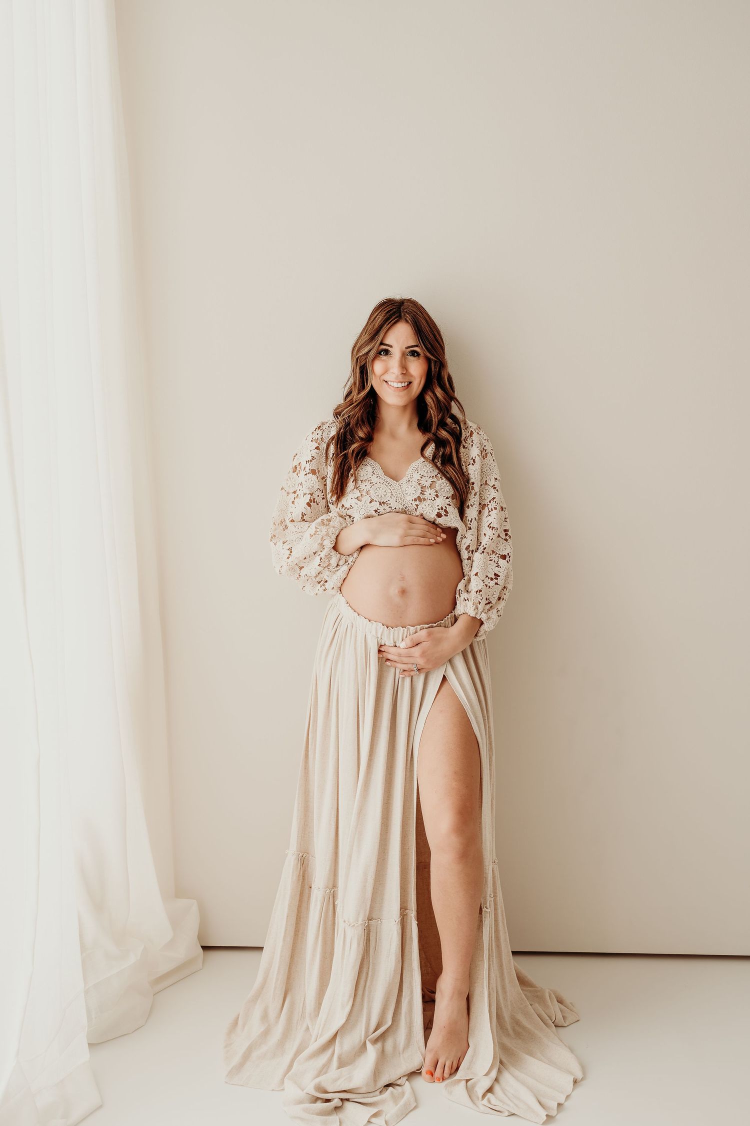 Ethereal maternity session featuring floral dress and natural poses in minimalist studio setting.