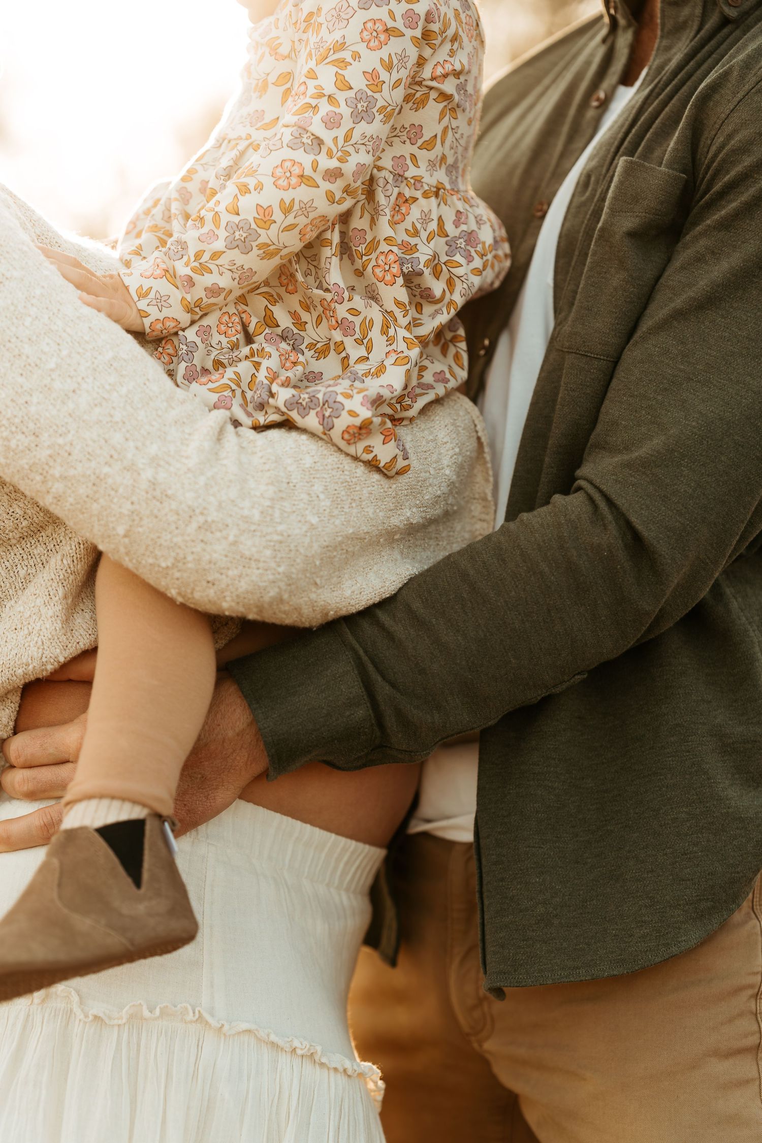 Gentle embraces captured in neutral tones with flowing white lace dress details. Maternity sunset photos.