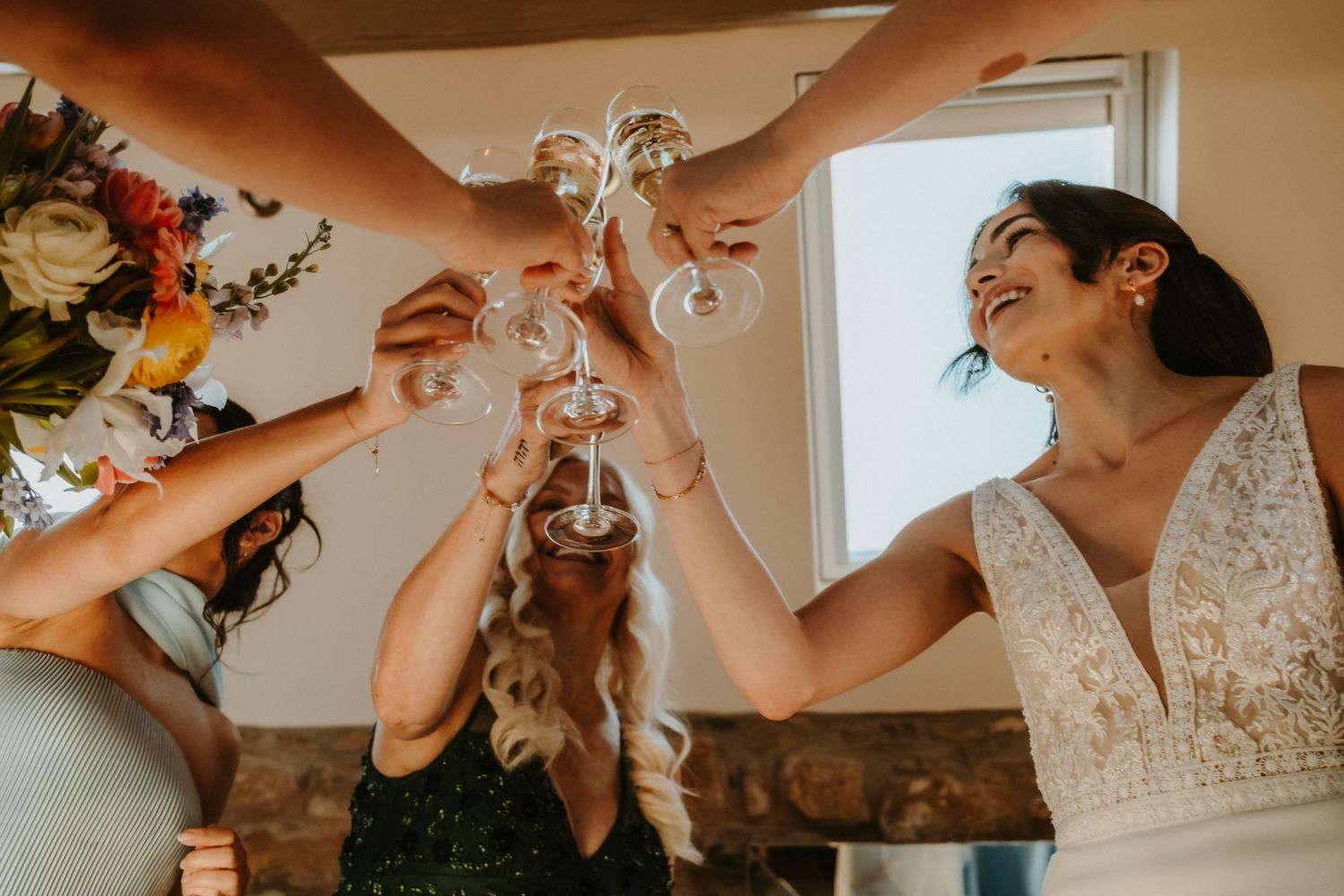 Bridesmaids and bride toasting with champagne glasses at a wedding celebration.