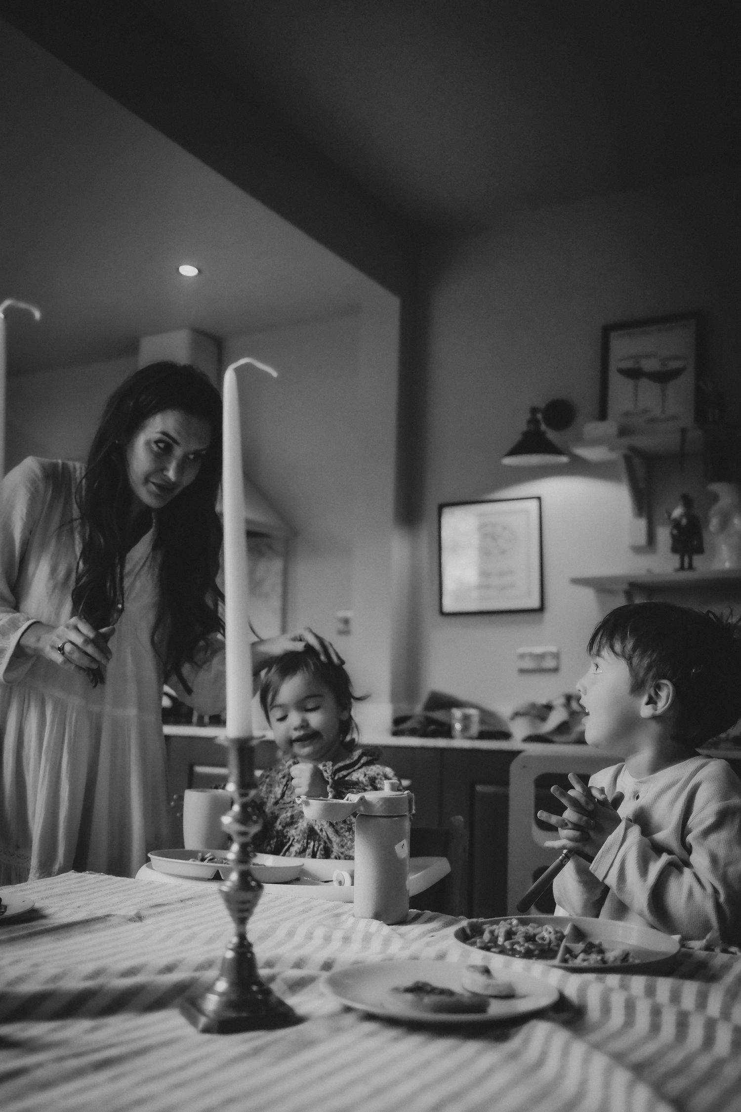 Black and white photo of a mother and two young children sharing a candlelit dinner.