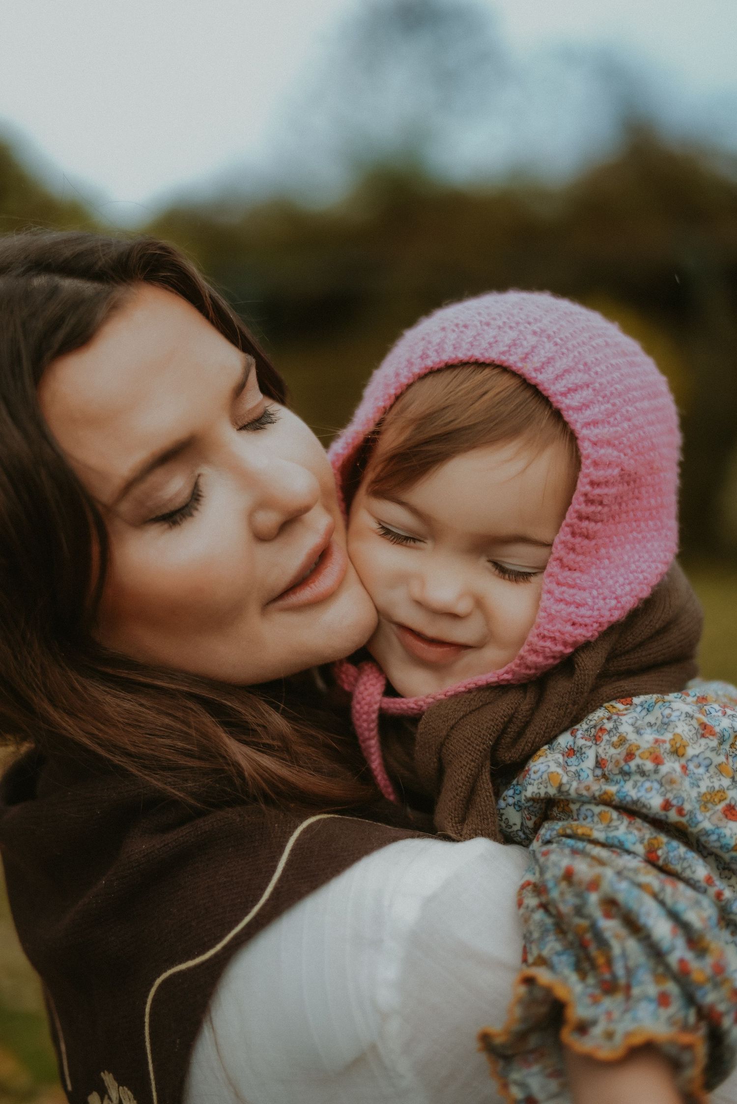 Mother and her little girl tight hug and cuddles with eyes closed