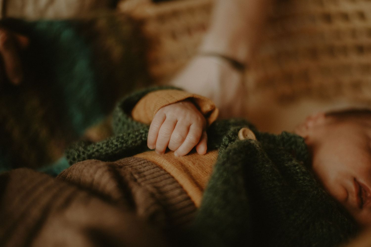 newborn hand and knitted cardigan in earthy tones.