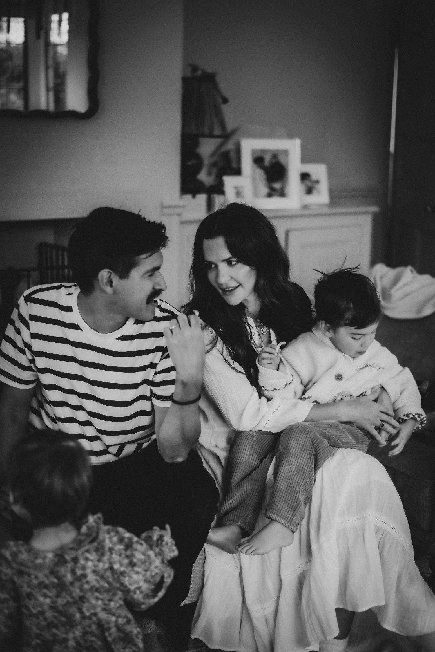 Black and white candid of a happy family laughing together in a cozy living room setting.