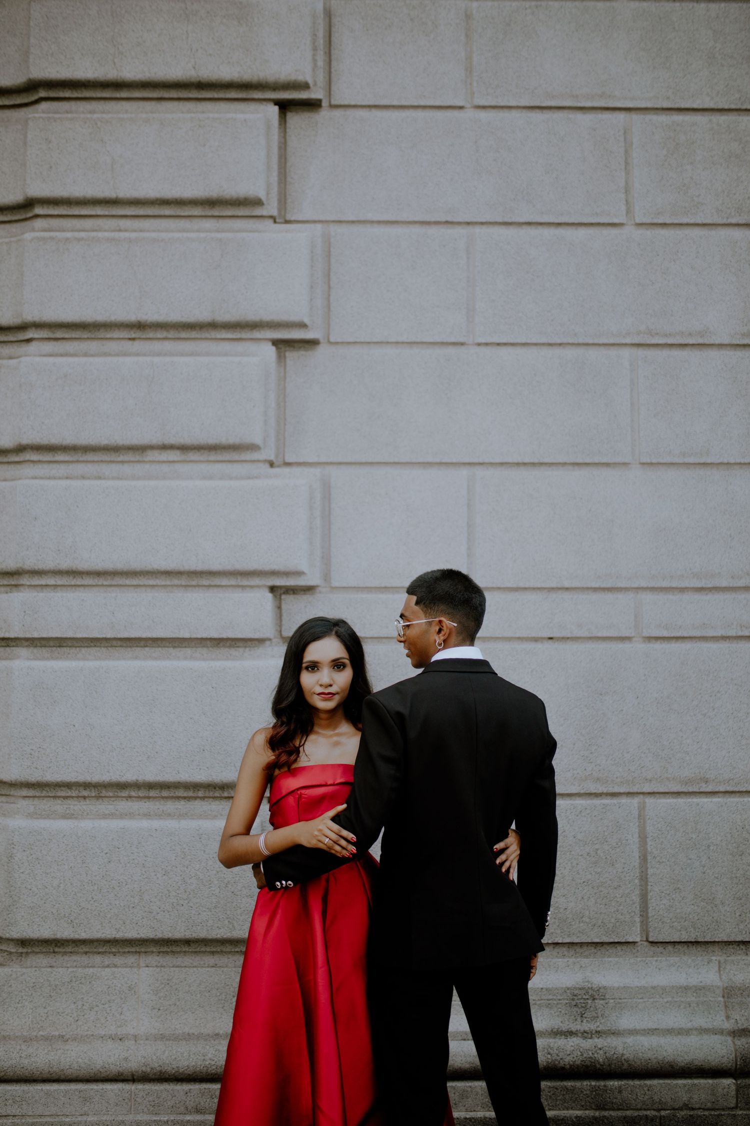 Couple portrait against minimal architectural wall, editorial style