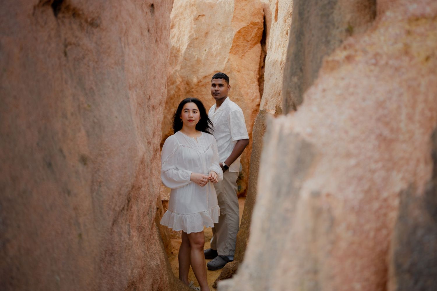 Elegant couple portrait framed between natural rock formations, creating a romantic and editorial-inspired composition.