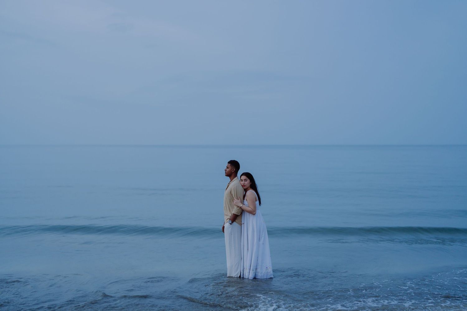 Intimate beach portrait of a couple embracing at sunset, photographed in a timeless and natural style.