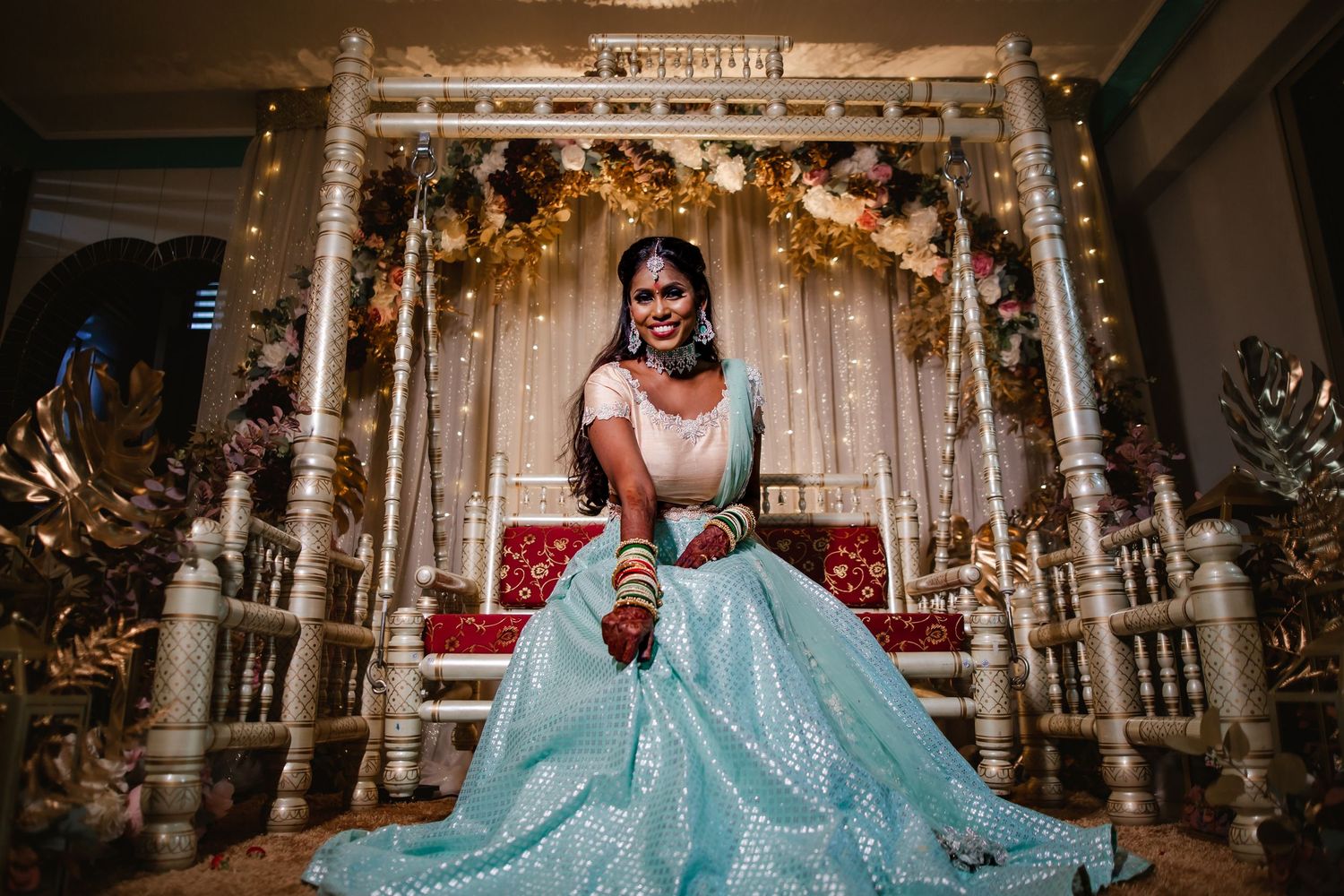 Bride seated on decorated stage with elegant gown, reception portrait Singapore