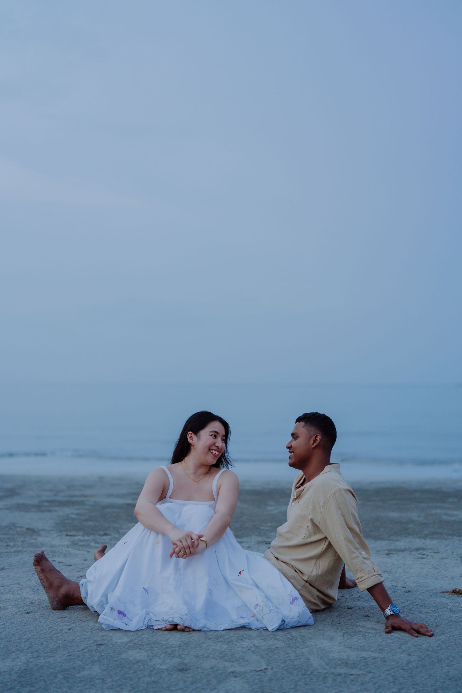 Romantic beach couple portrait during a pre-wedding photoshoot, captured with natural light and soft blue tones.