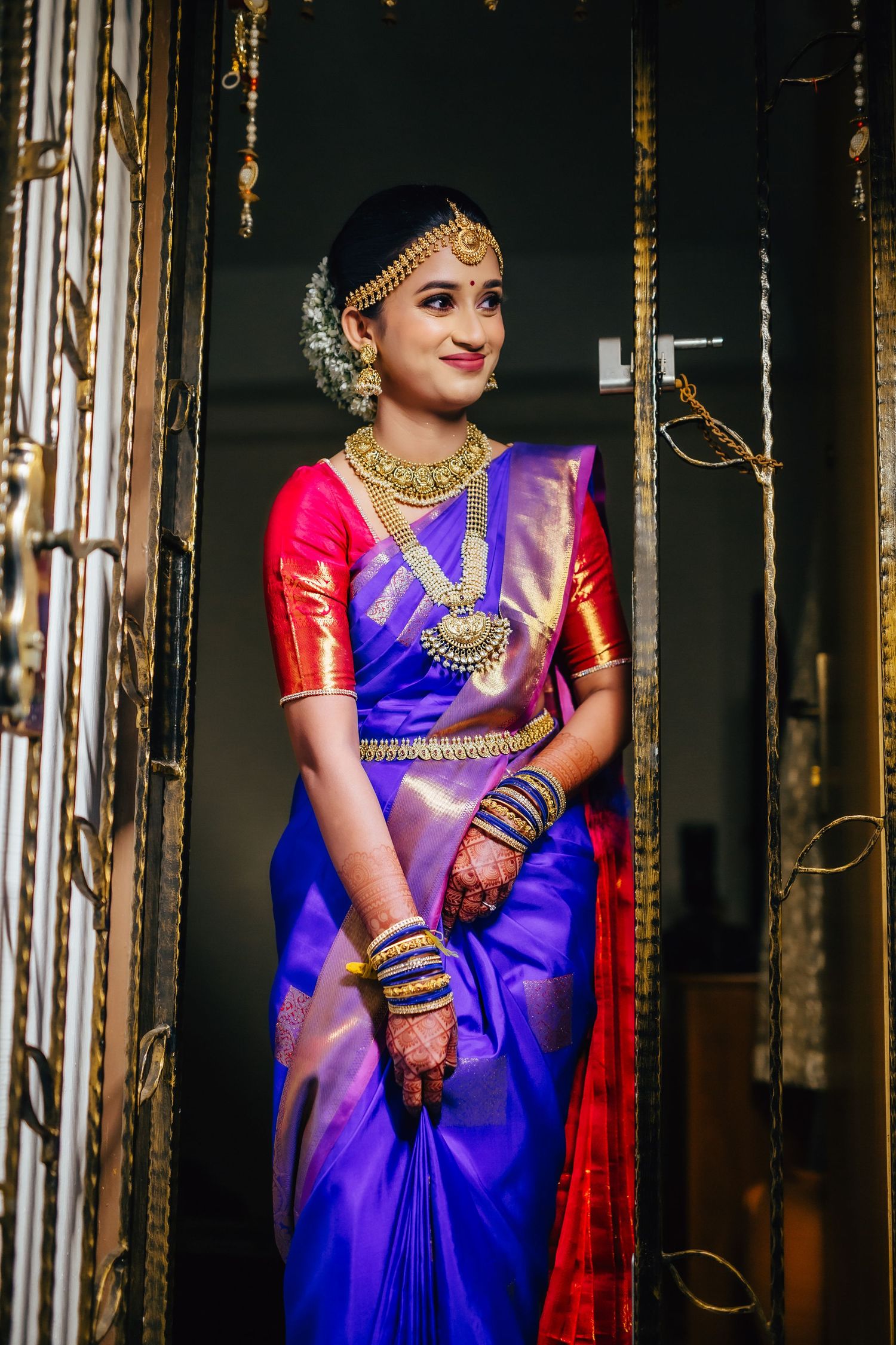 Bride portrait in saree standing near doorway, traditional elegance