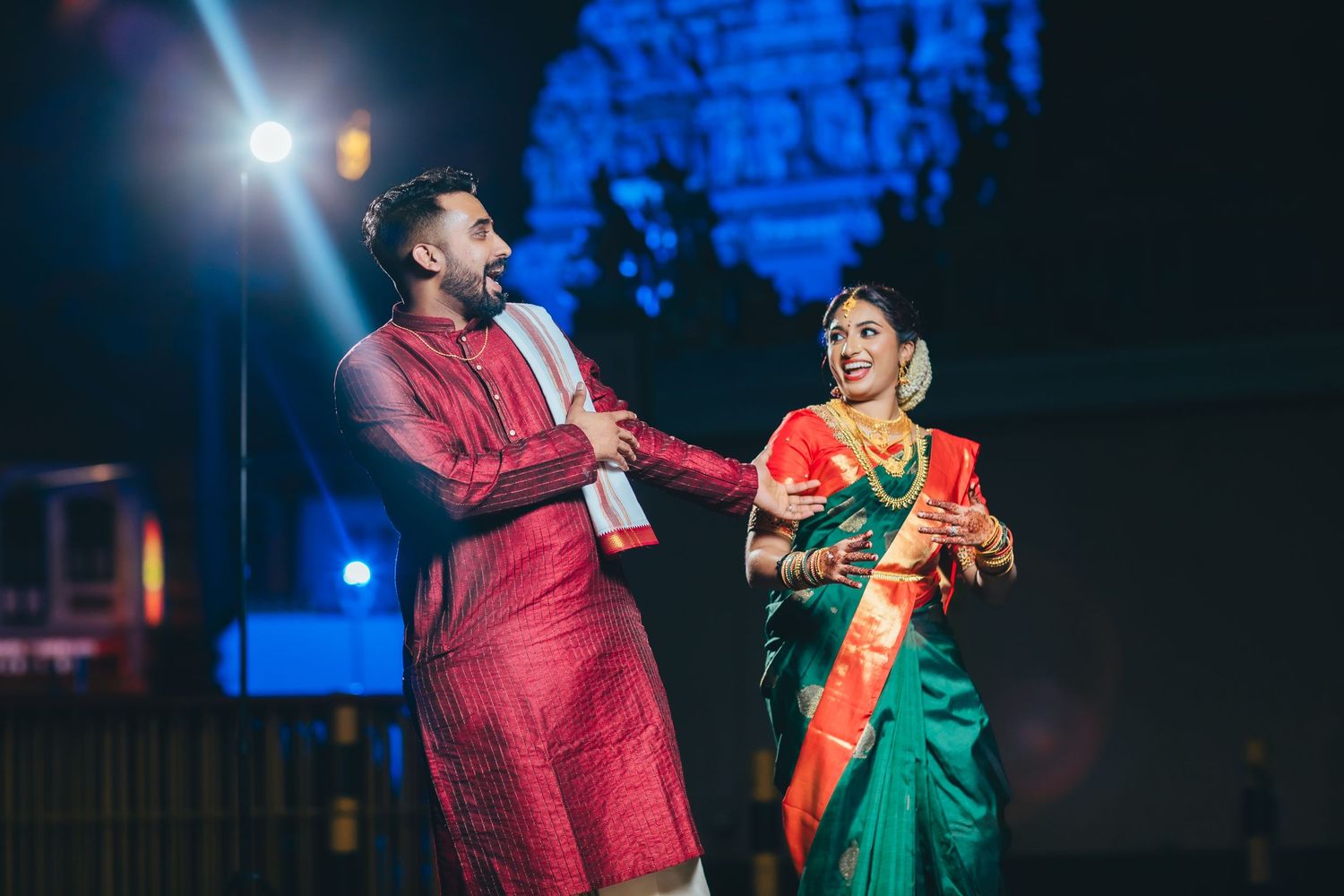 Couple dancing in traditional attire under lights, festive moment