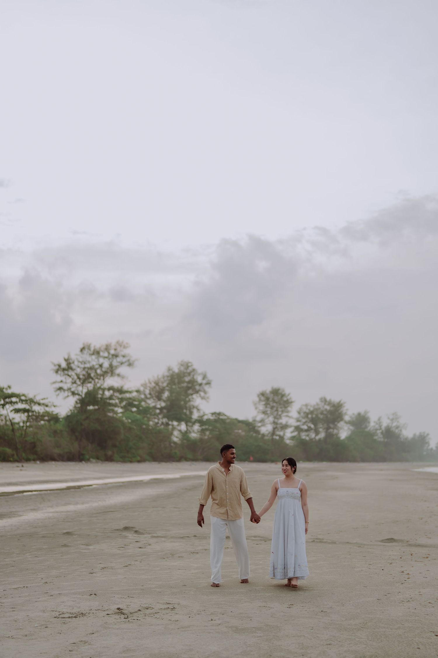 Elegant couple portrait on a quiet beach, capturing genuine connection and emotion.