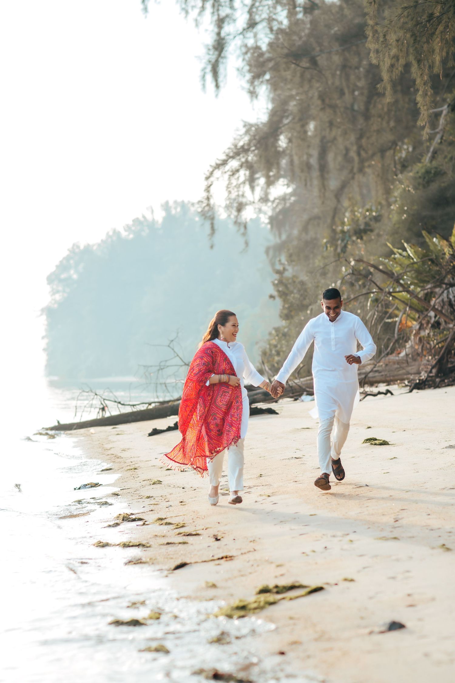 Couple walking along beach shoreline, romantic outdoor shoot