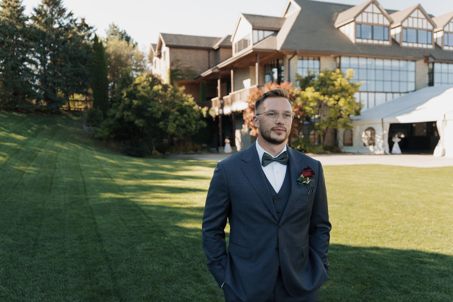 Groom waiting on the lawn before first look as bride appears in the distance at The Manor in King City Jewish wedding.