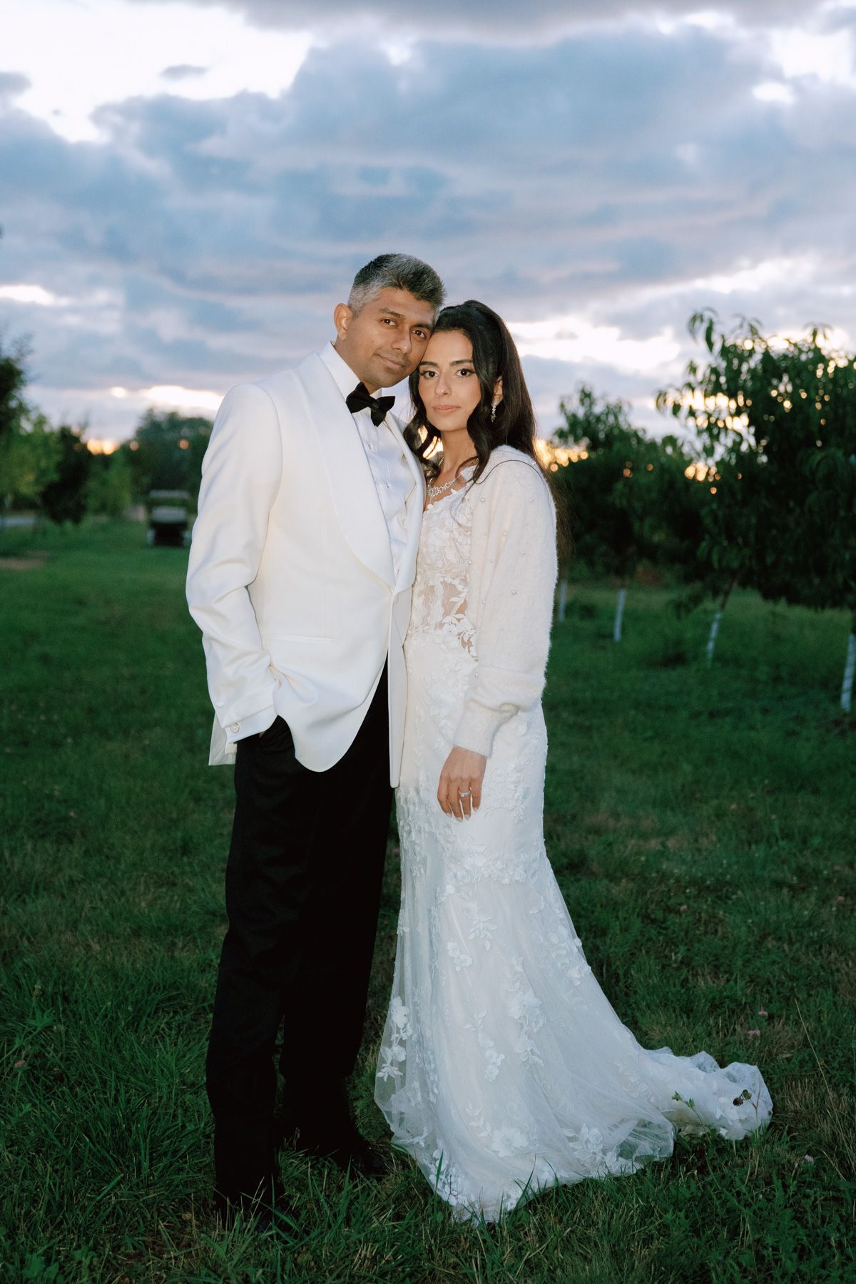 Bride and groom posing in a grassy field at dusk at Kurtz Orchards in Niagara-on-the-Lake for romantic wedding photography.