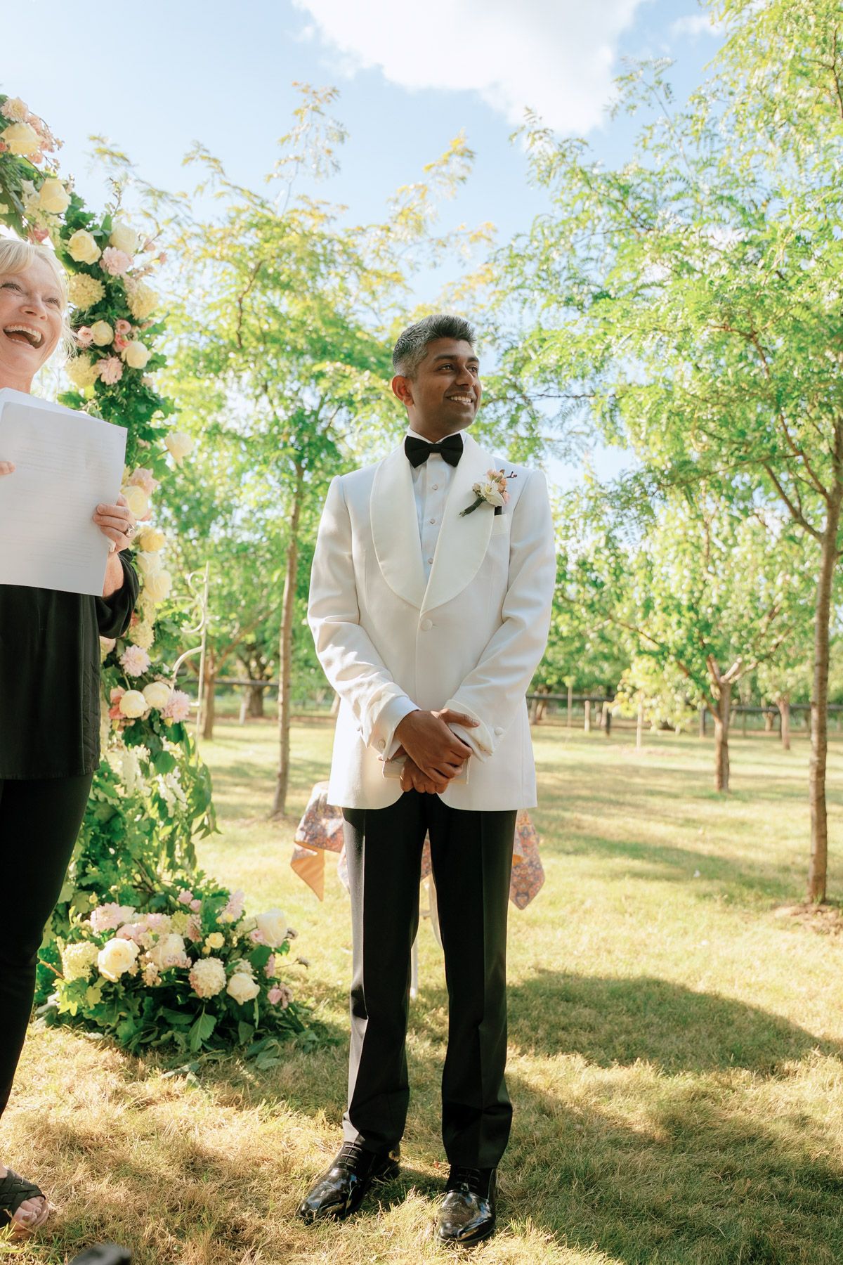 Groom in white tuxedo jacket at the outdoor ceremony altar at Kurtz Orchards in Niagara-on-the-Lake for wedding photography.