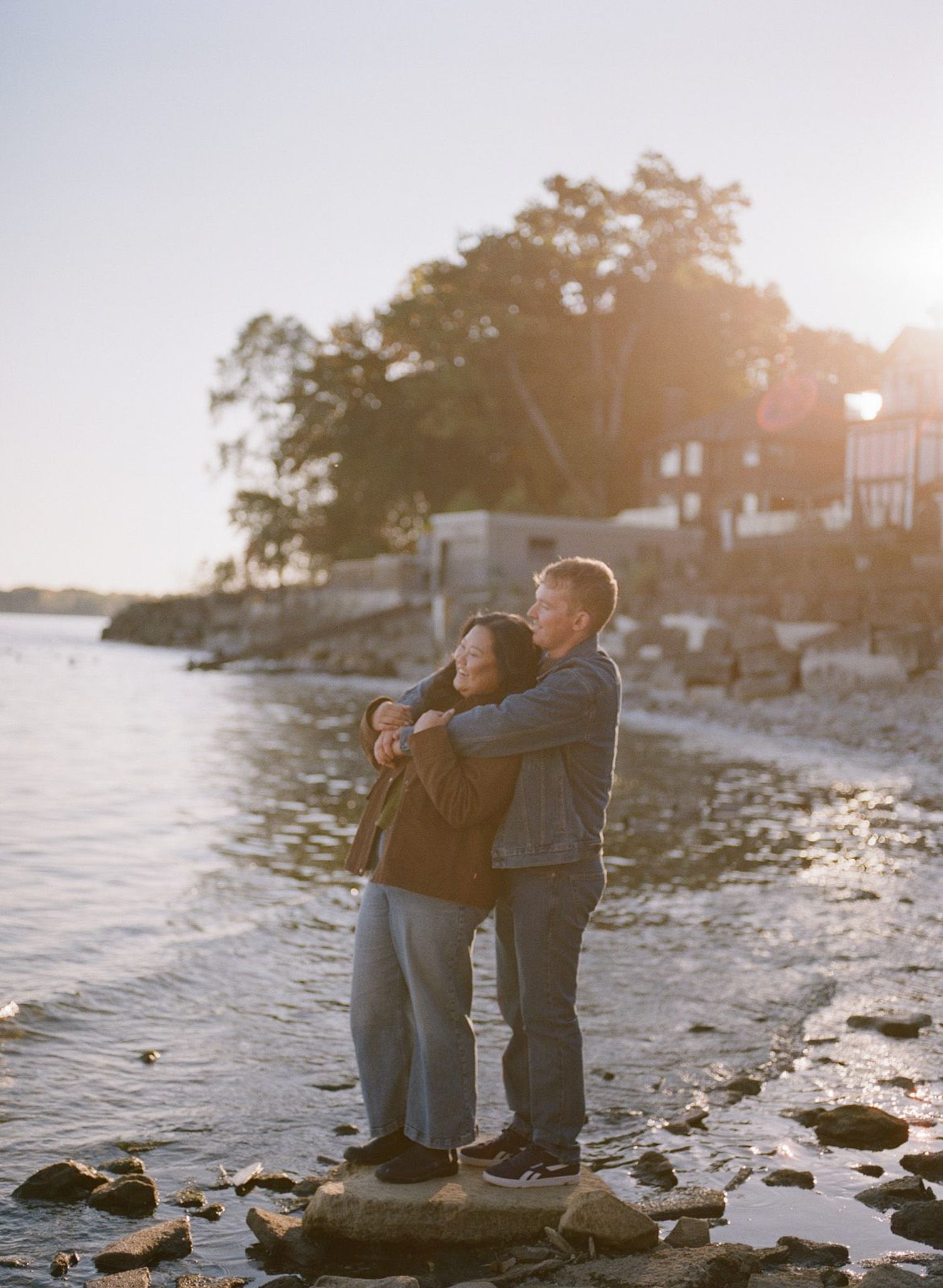 Couple embracing on a rocky shoreline in Mississauga at golden hour during their pre-wedding portrait session