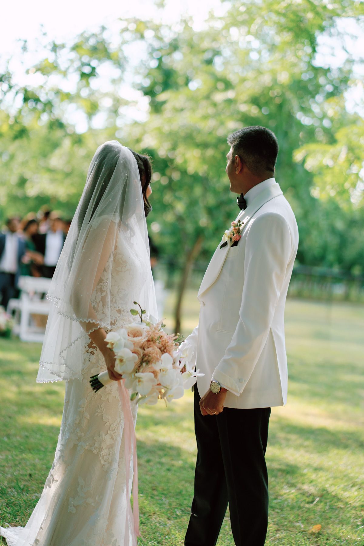 Bride with bouquet beside groom in white tuxedo at Kurtz Orchards in Niagara-on-the-Lake outdoor wedding ceremony.
