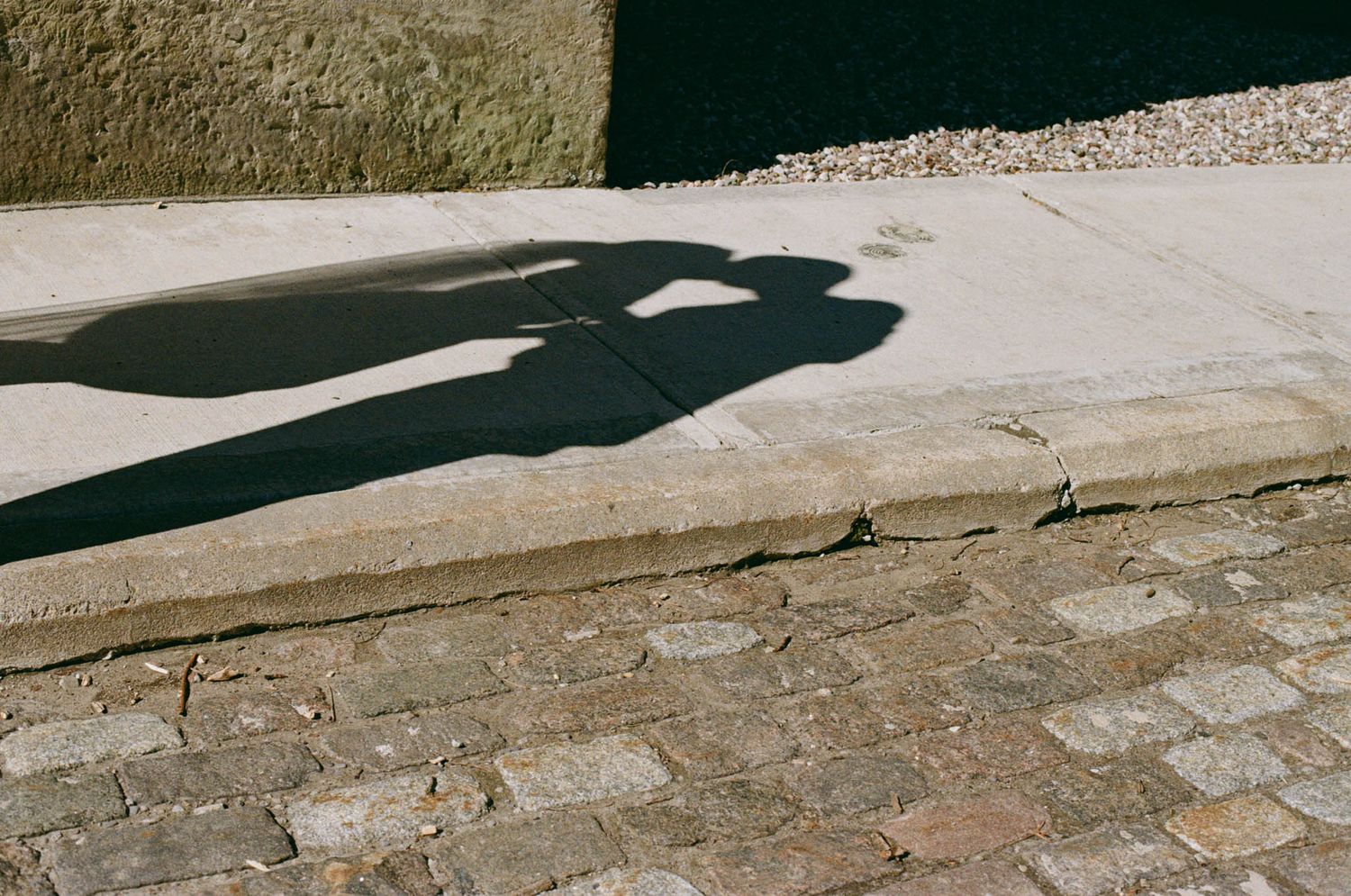 Couple’s shadow embracing on sunlit cobblestone outside Osgoode Hall during a Toronto City Hall wedding portrait session.