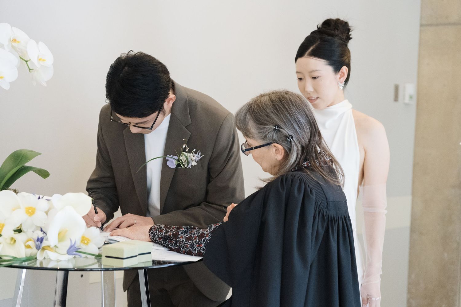 Couple signing legal wedding documents with officiant at Toronto City Hall for intimate ceremony photography.