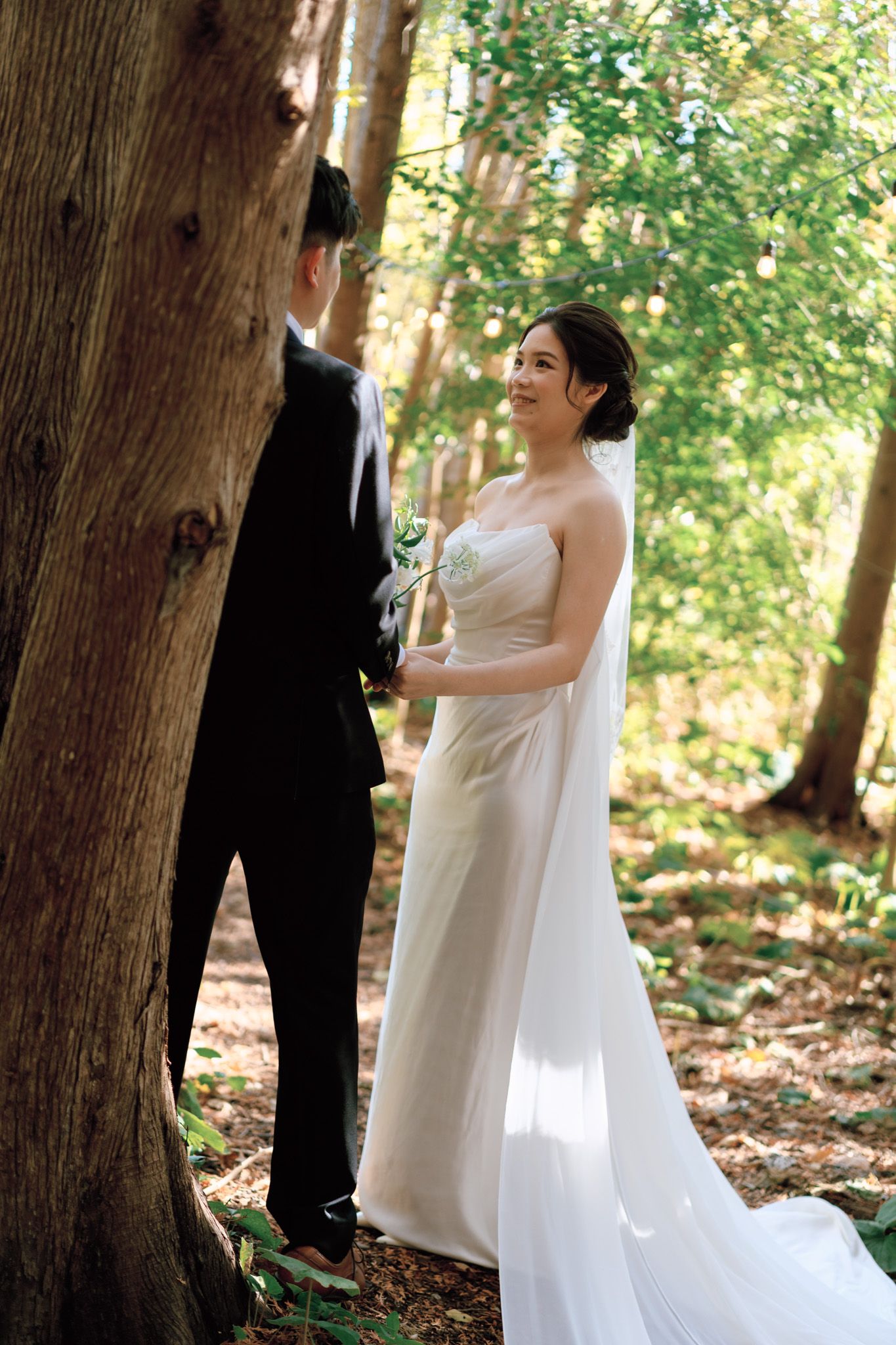 Bride smiling at groom among sunlit forest trees at Razi Estate in Schomberg for cinematic forest wedding photography.