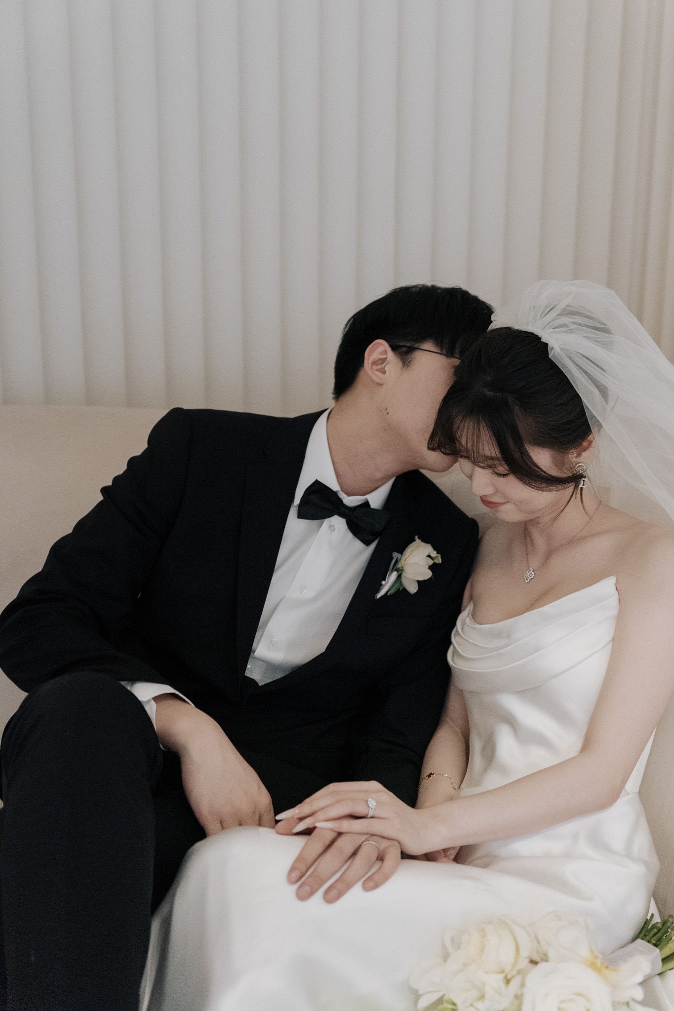 Bride and groom sitting close as he kisses her at Archive Studio in Toronto for romantic editorial wedding photography.